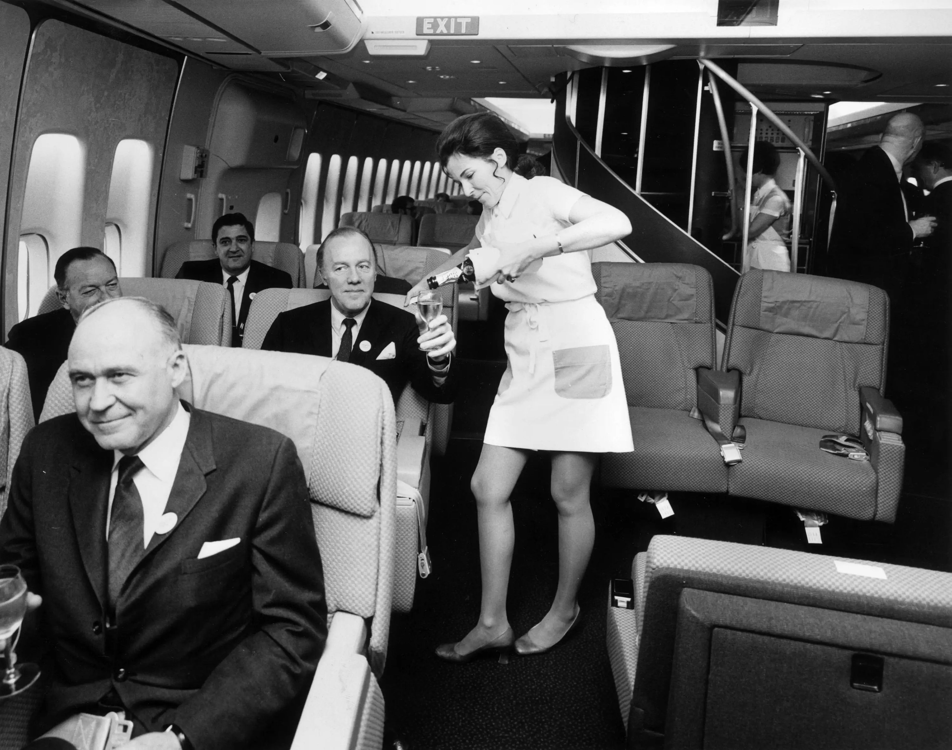 Una azafata sirve champán a los pasajeros de primera clase en un Boeing 747.