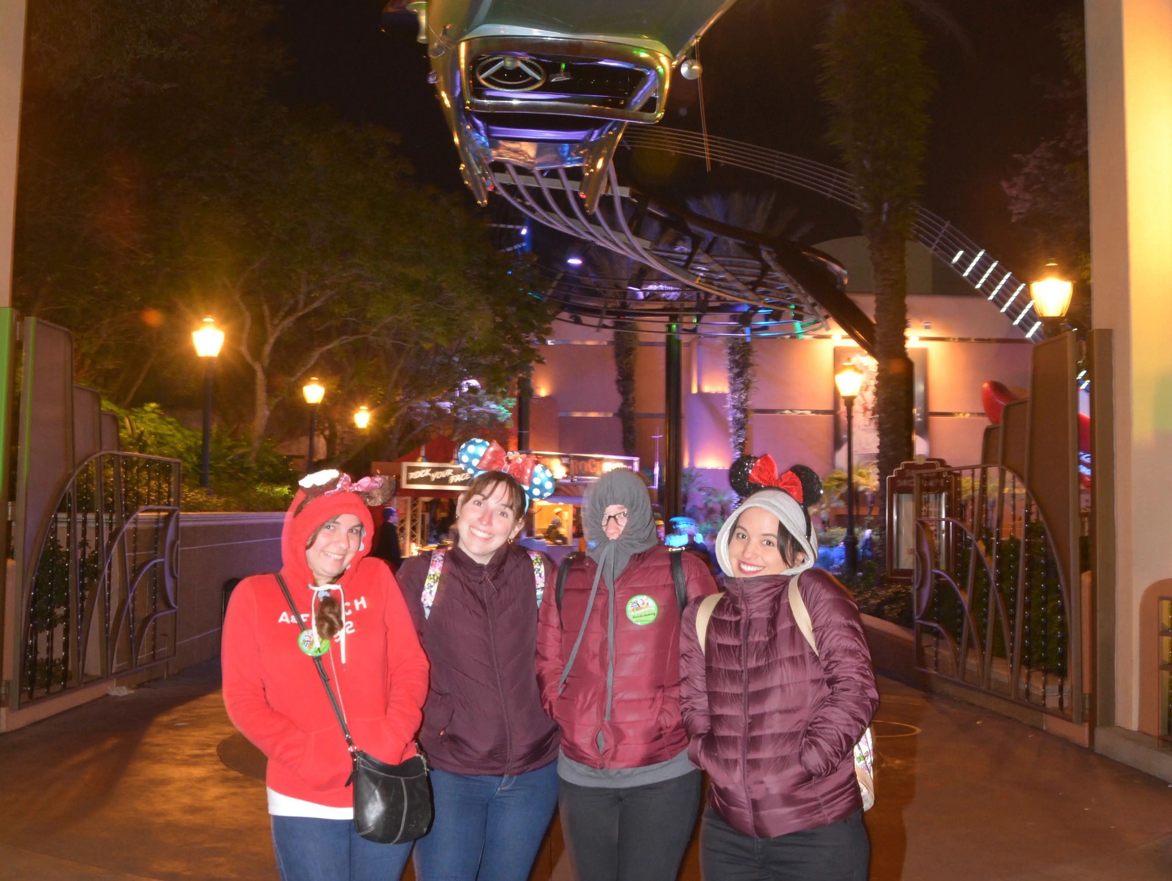 group of friends posing for a photo under rock n roller coaster sign at hollywood studios in disney world