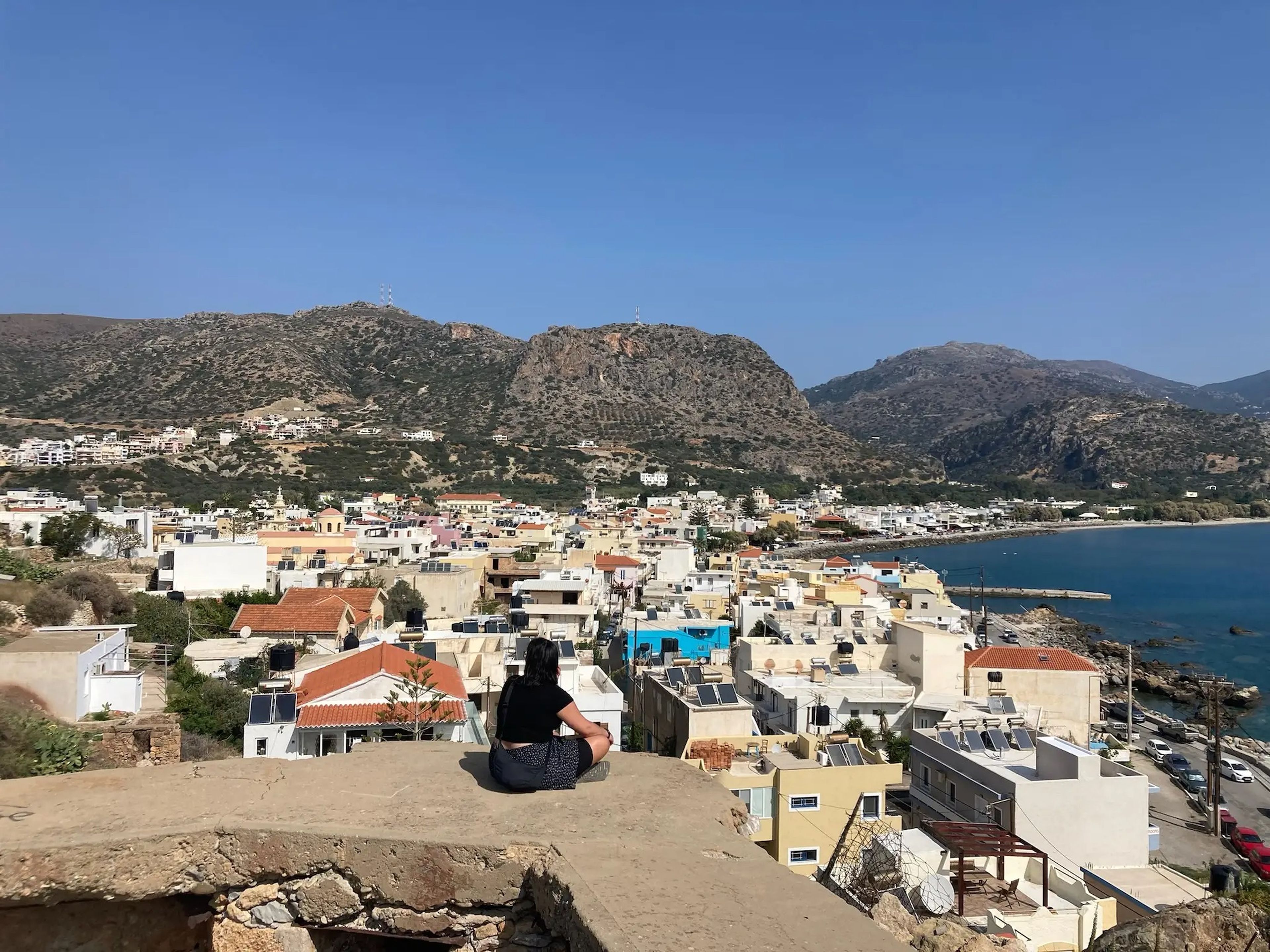 hanna sitting on a ledge overlooking crete at rethymno
