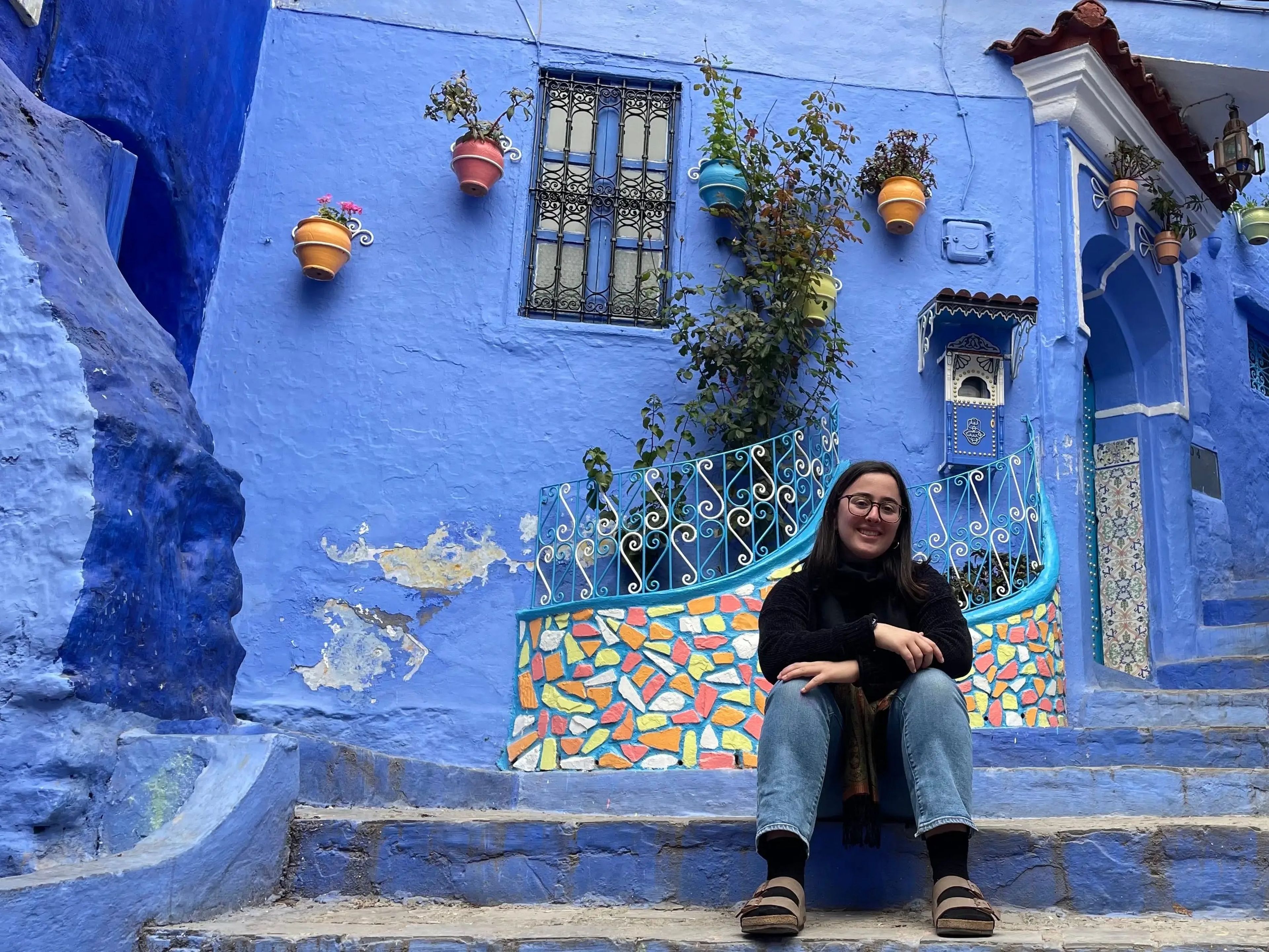 hannah sitting in front of a blue house in morocco