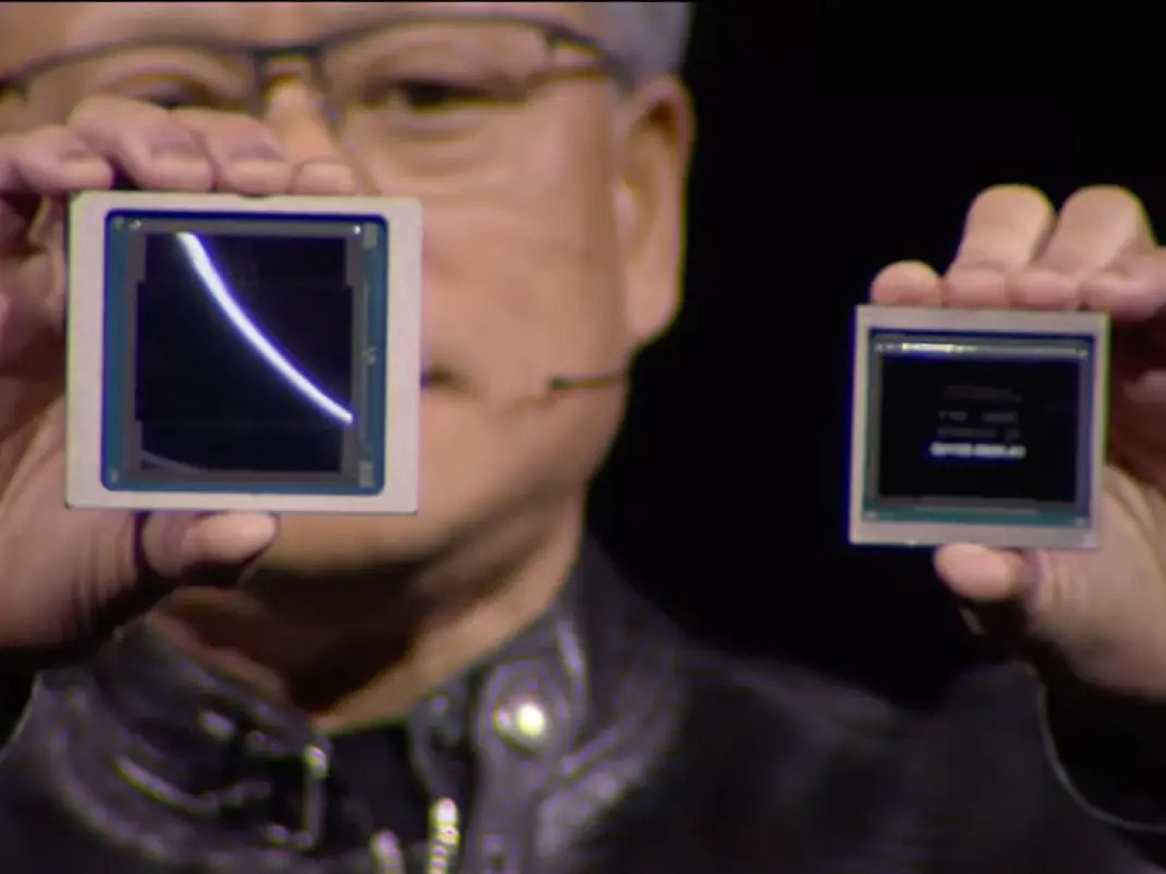Huang holds up two chips while speaking onstage at the GTC conference.