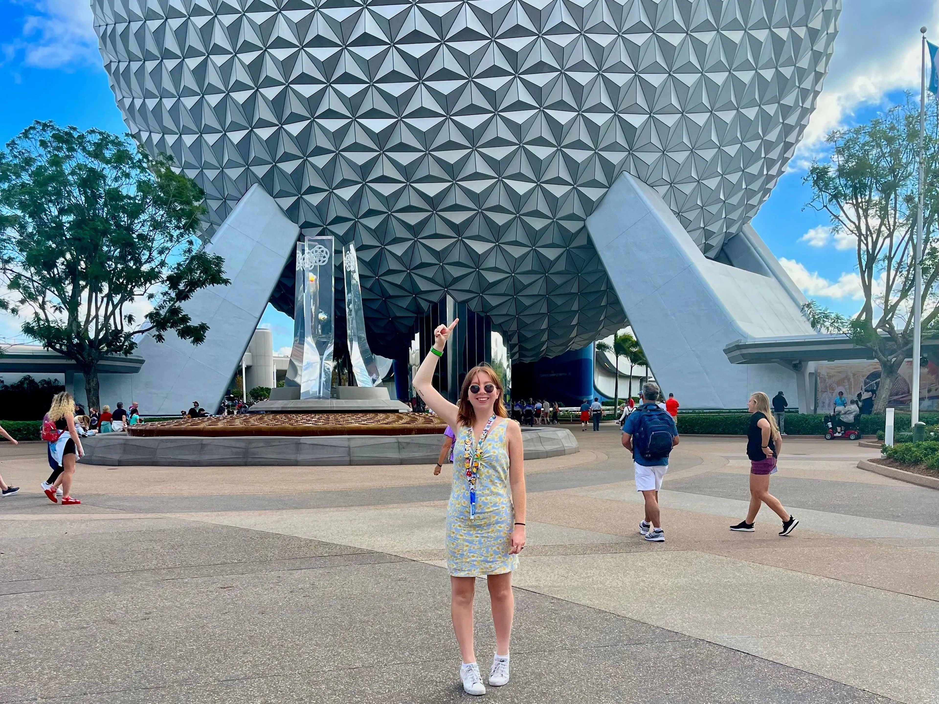 jordyn pointing up at the epcot ball at the disney world theme park