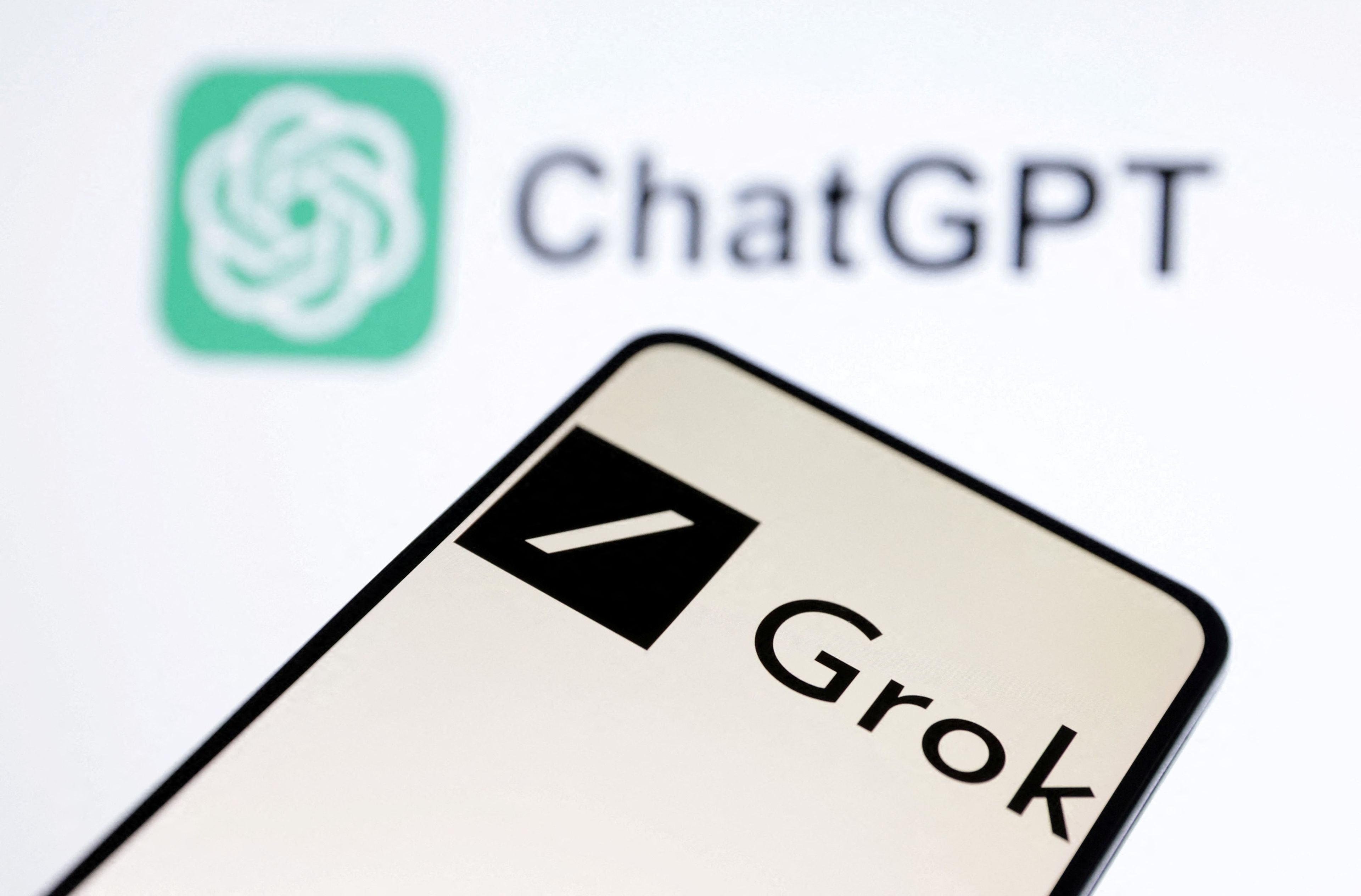 Un móvil que muestra la imagen del logo de Grok, el chatbot de Elon Musk, frente al logo de ChatGPT.