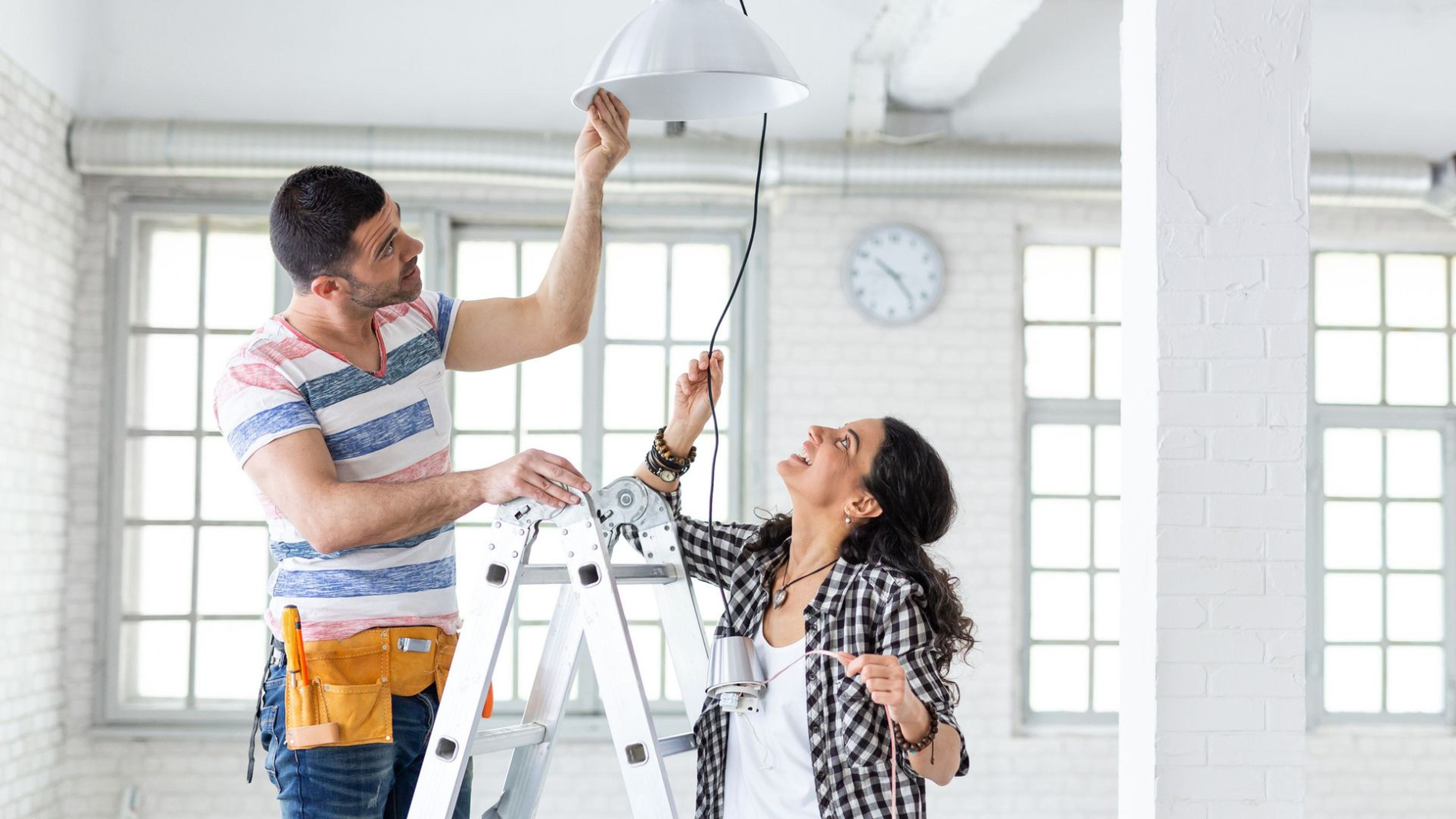 Una pareja instala una lámpara en su casa nueva.