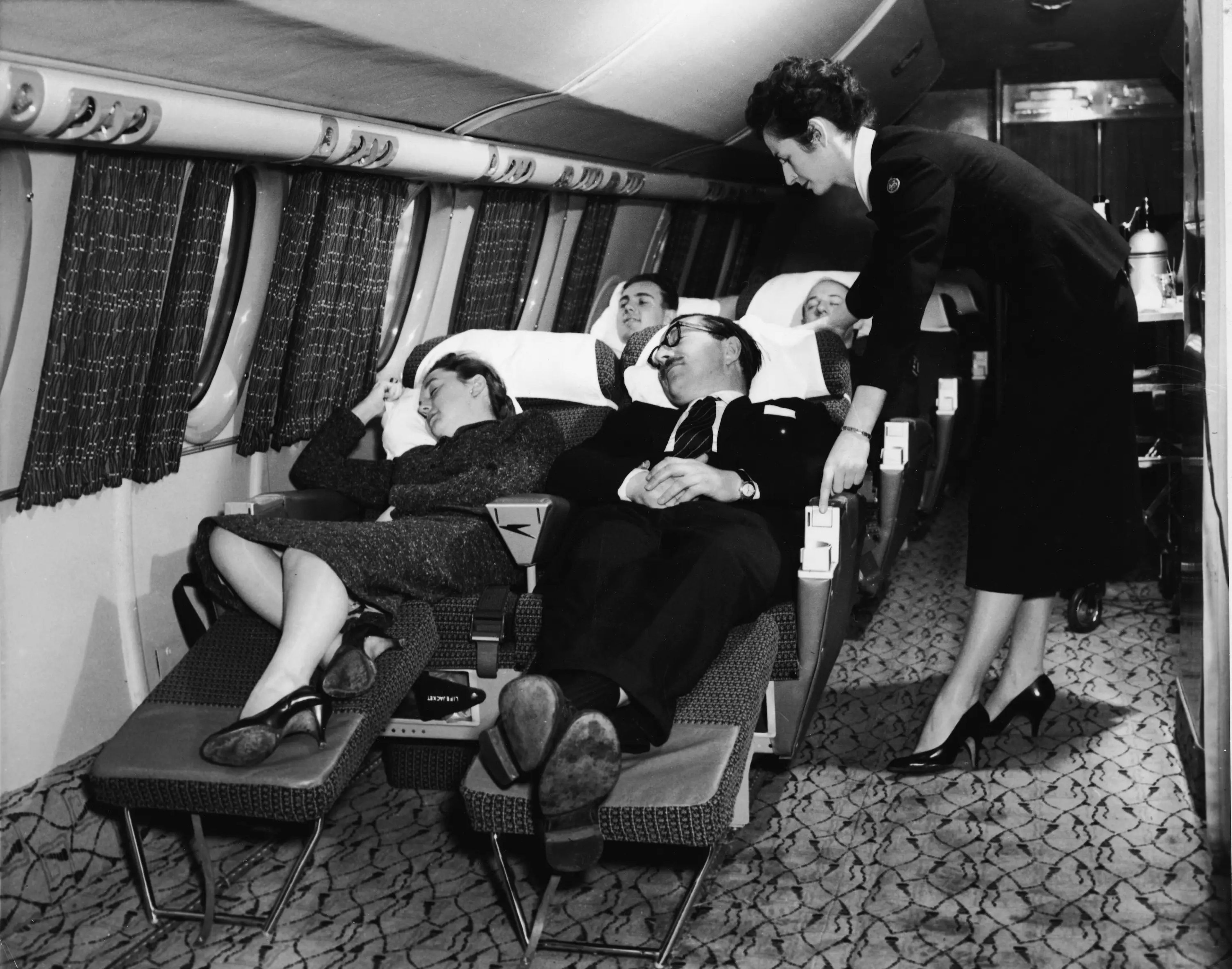 Pasajeros recostados en sus asientos en un vuelo en primera clase en la década de 1950.