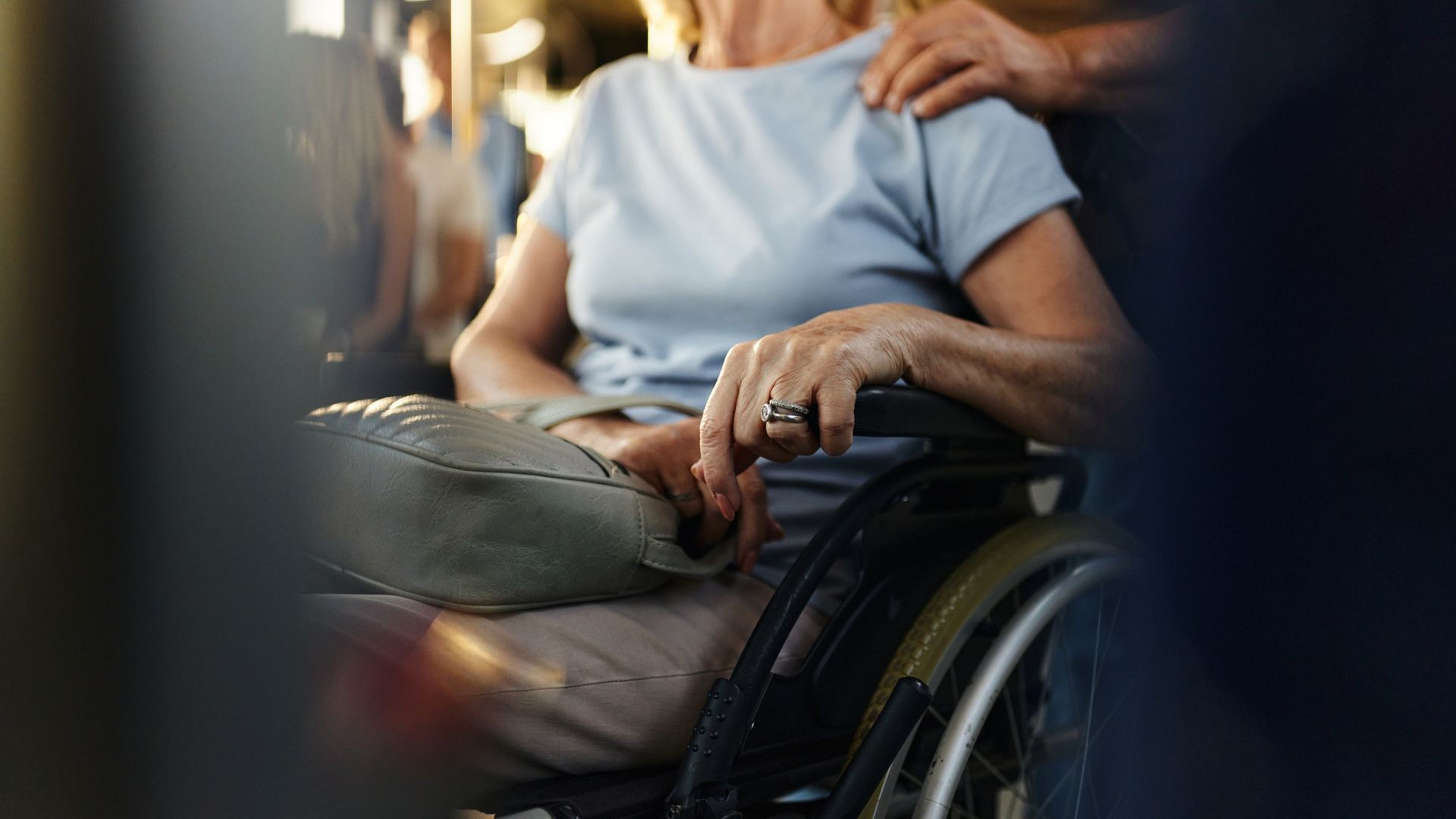 Una persona pone la mano en el hombro de una mujer en silla de ruedas.
