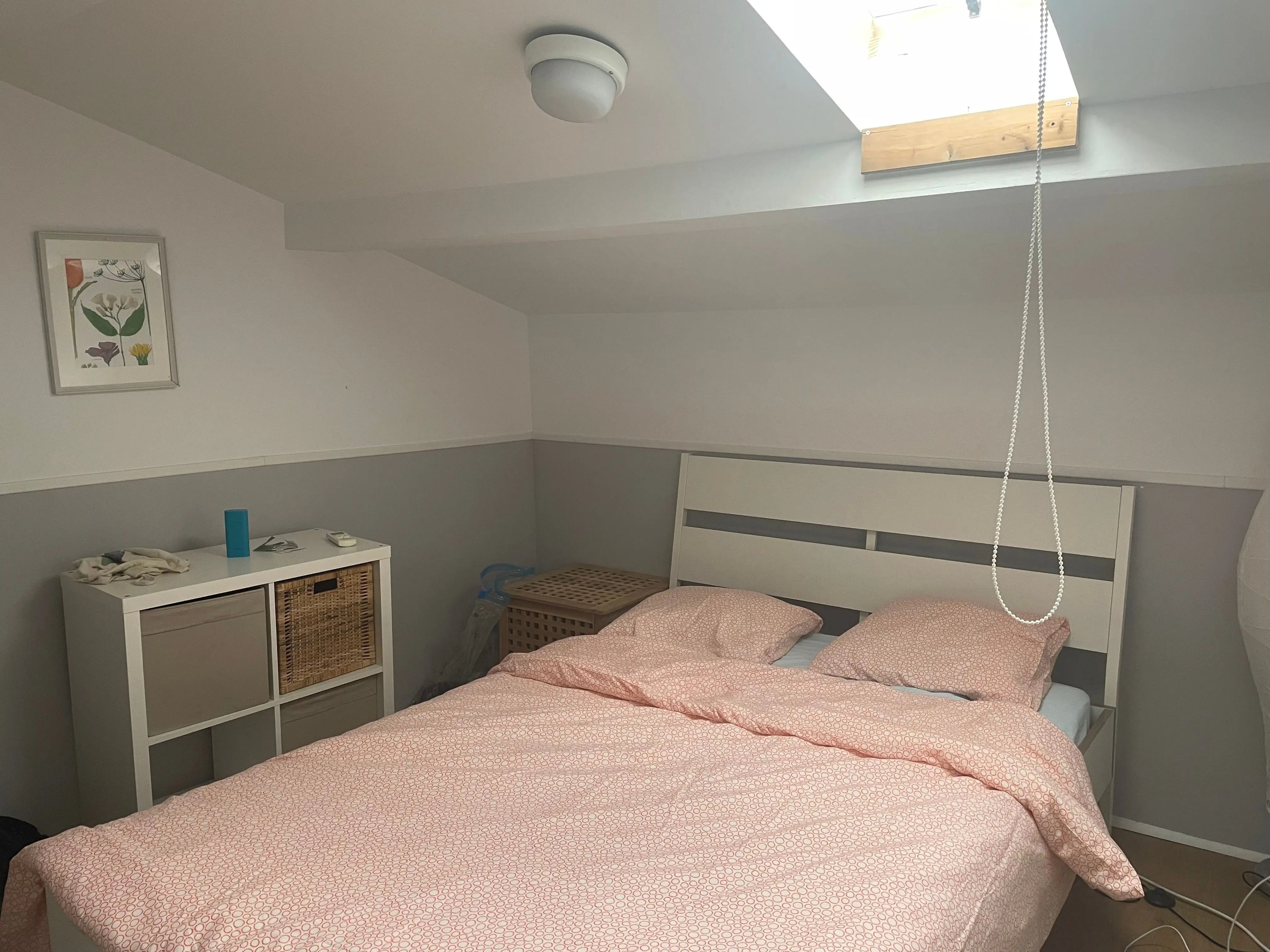 photo of a small bedroom in an airbnb with a pink bed and white furniture