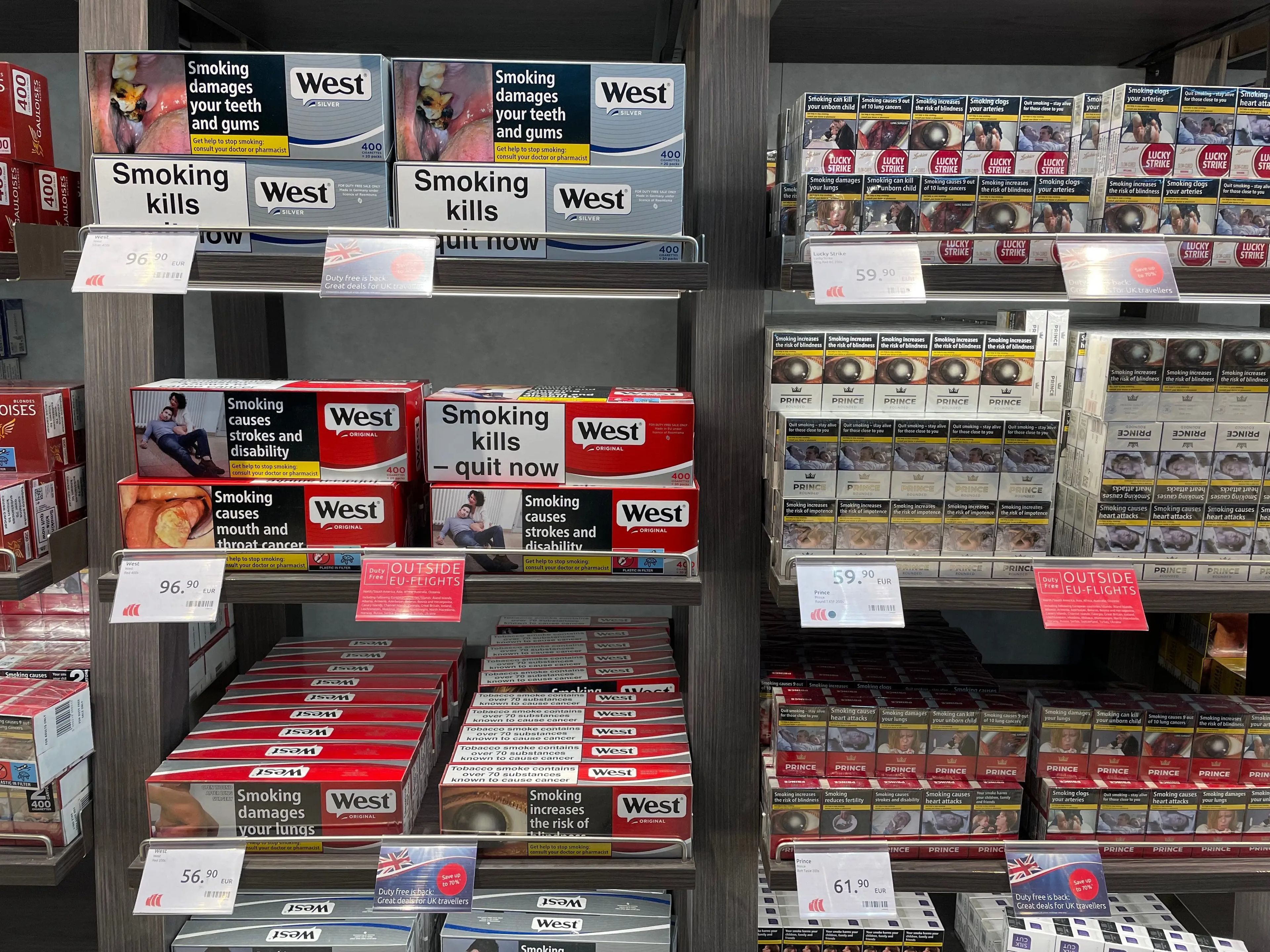 shelves of cigarette with signs that say smoking kills