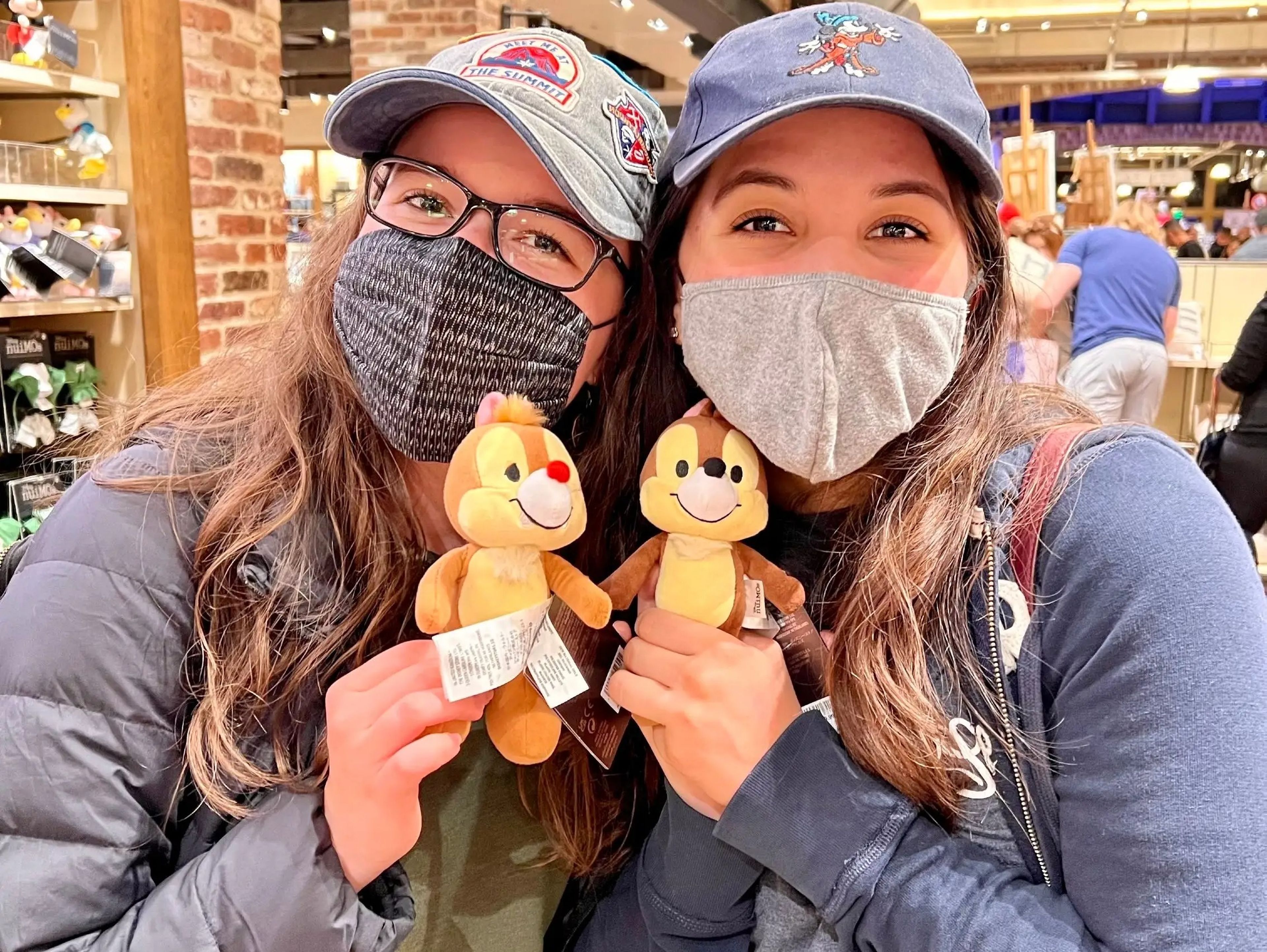 sofia and a friend holding up chip and dale stuffed animals in a merchandise shop in disney world