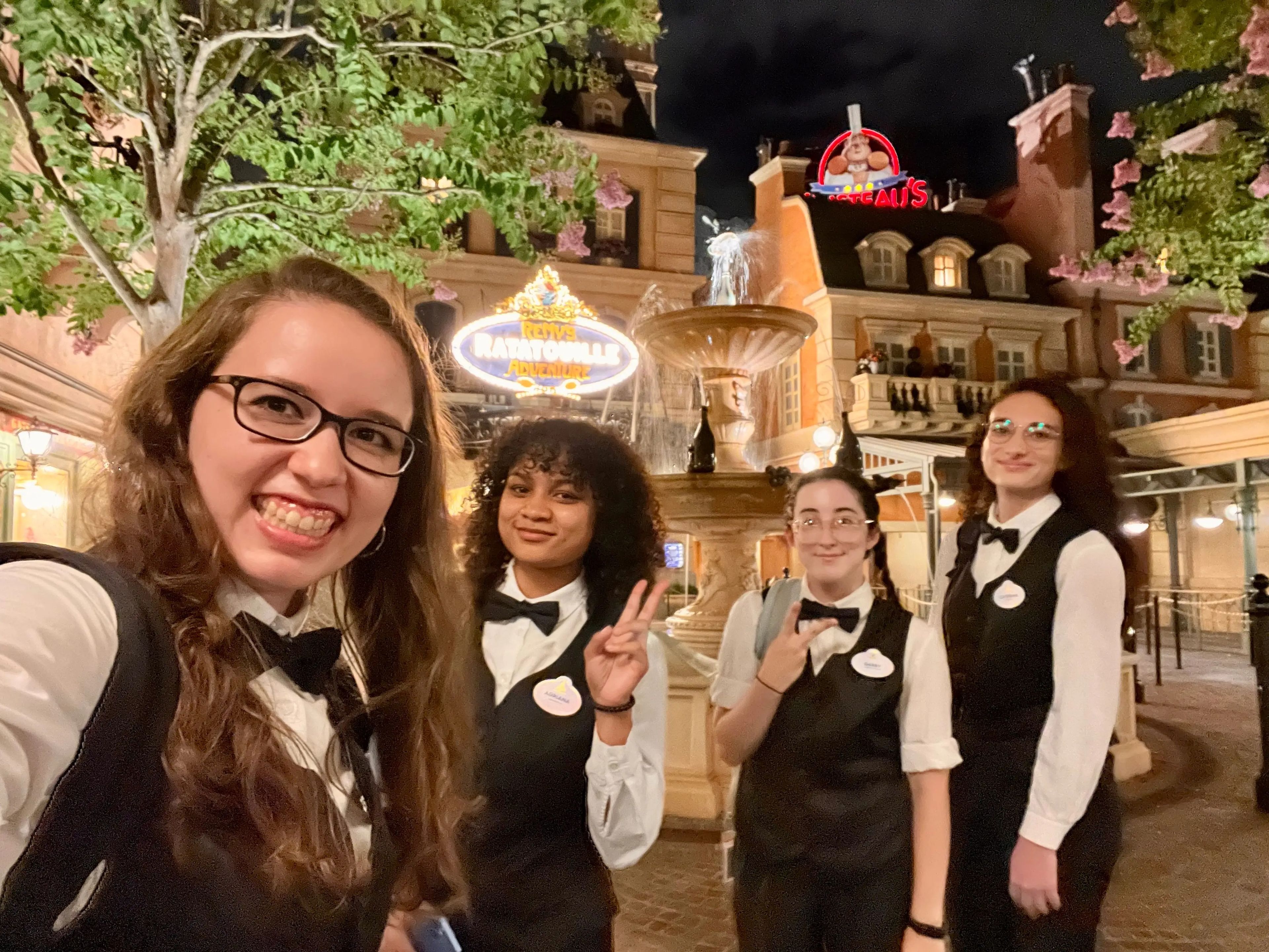sofia and three other cast members posing for a photo in the france pavilion at epcot in disney world