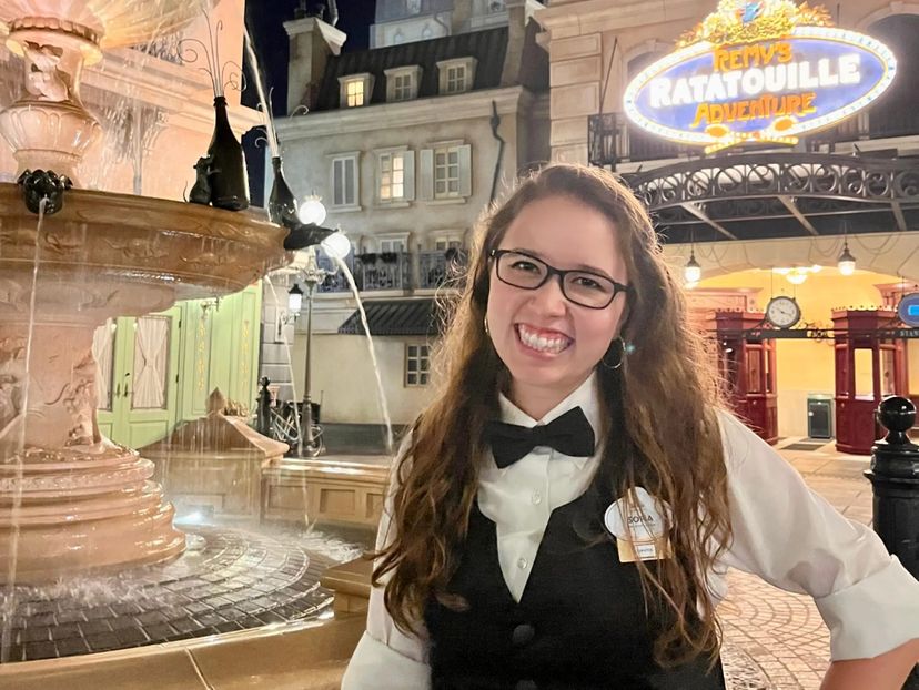 sofia posing for a photo in costume in the france pavilion at epcot in disney world