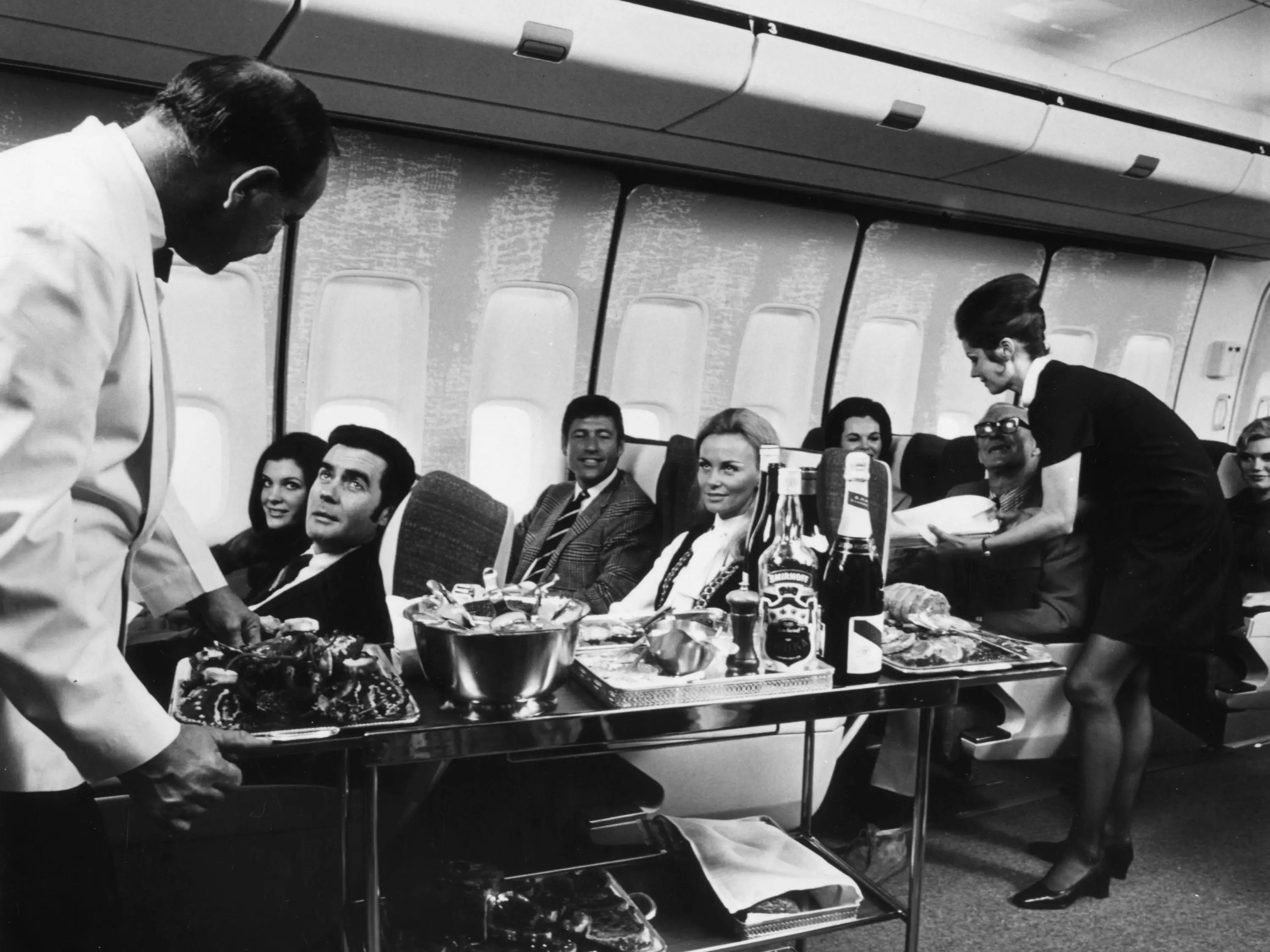 Los auxiliares de vuelo sirven bebidas y refrescos a los pasajeros de primera clase a bordo de un Boeing 747.