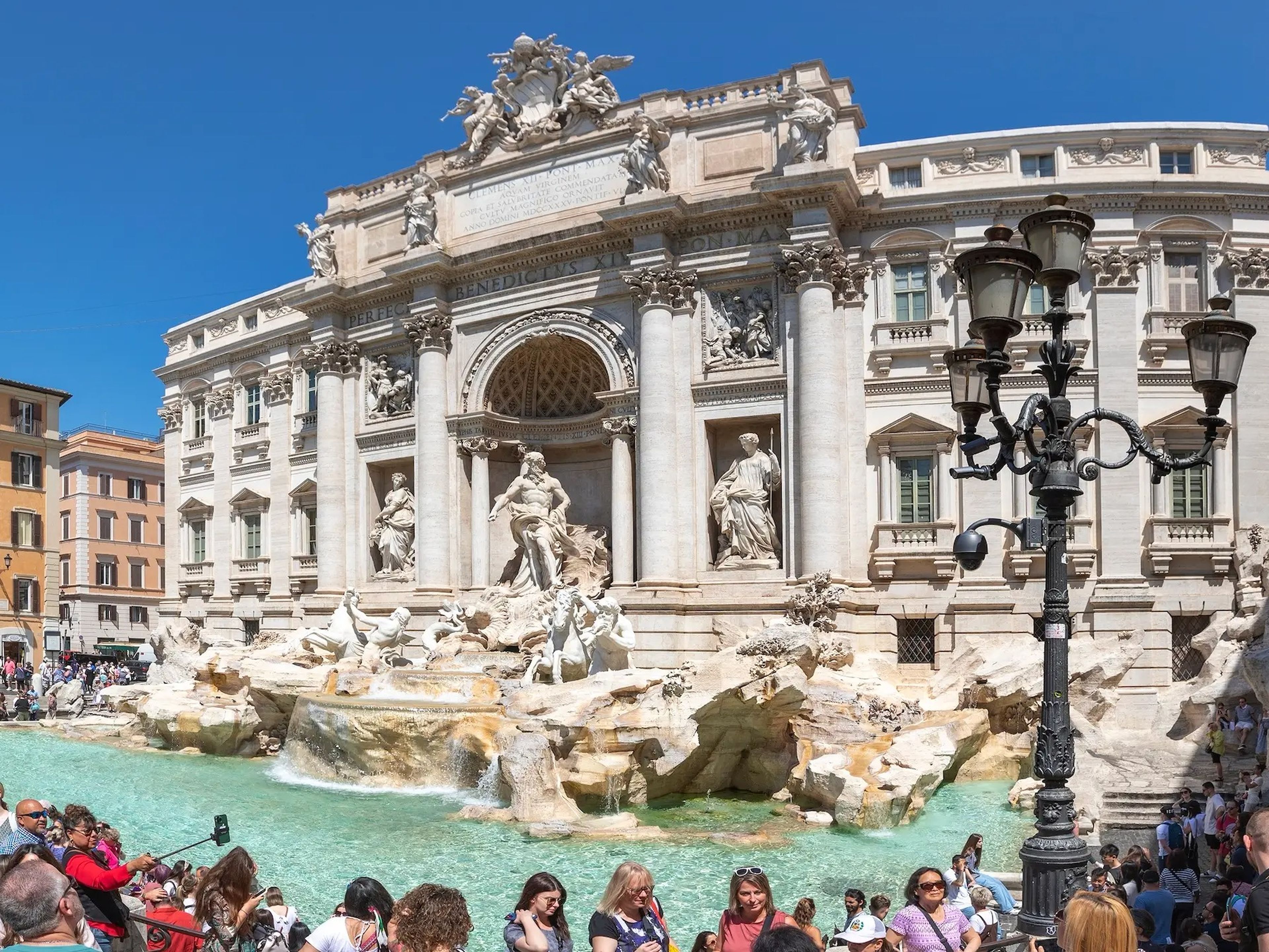 tourists crowding around trevi fountain in rome on a sunny day