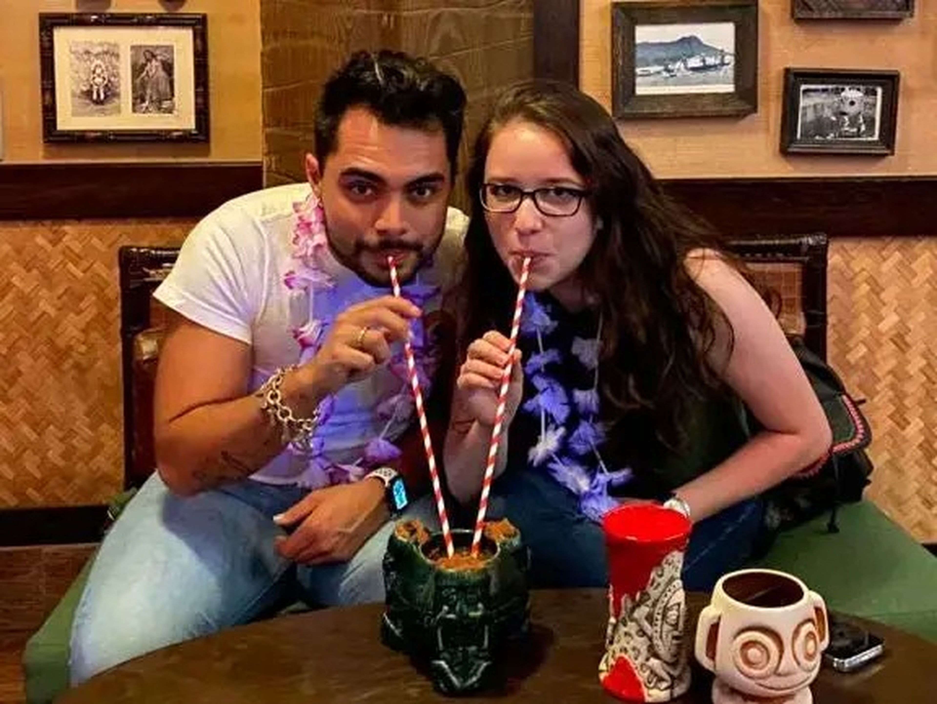 two people drinking out of a cocktail at trader sams bar at polynesian resort disney world
