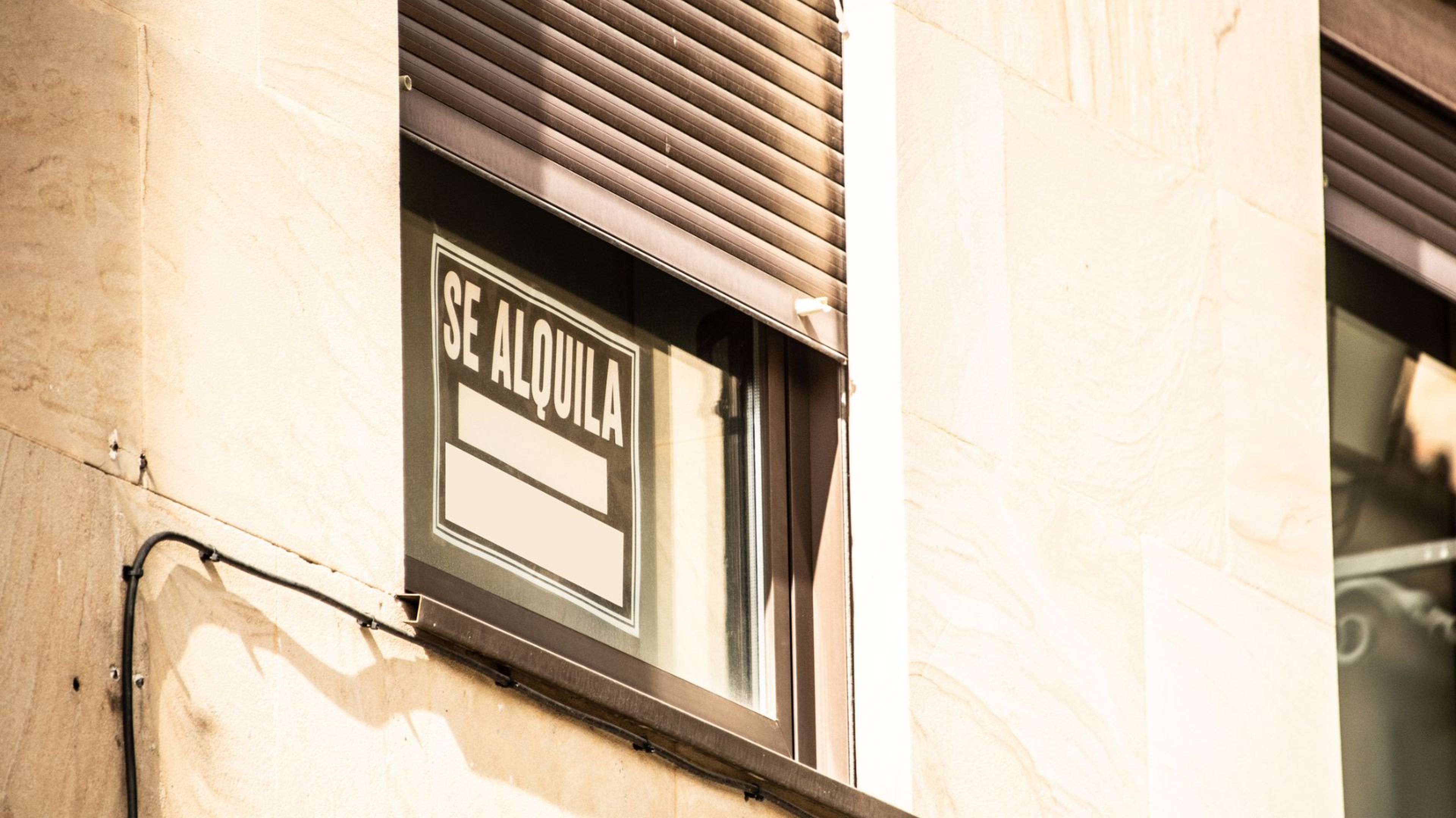 Un cartel de "Se alquila" en una ventana.