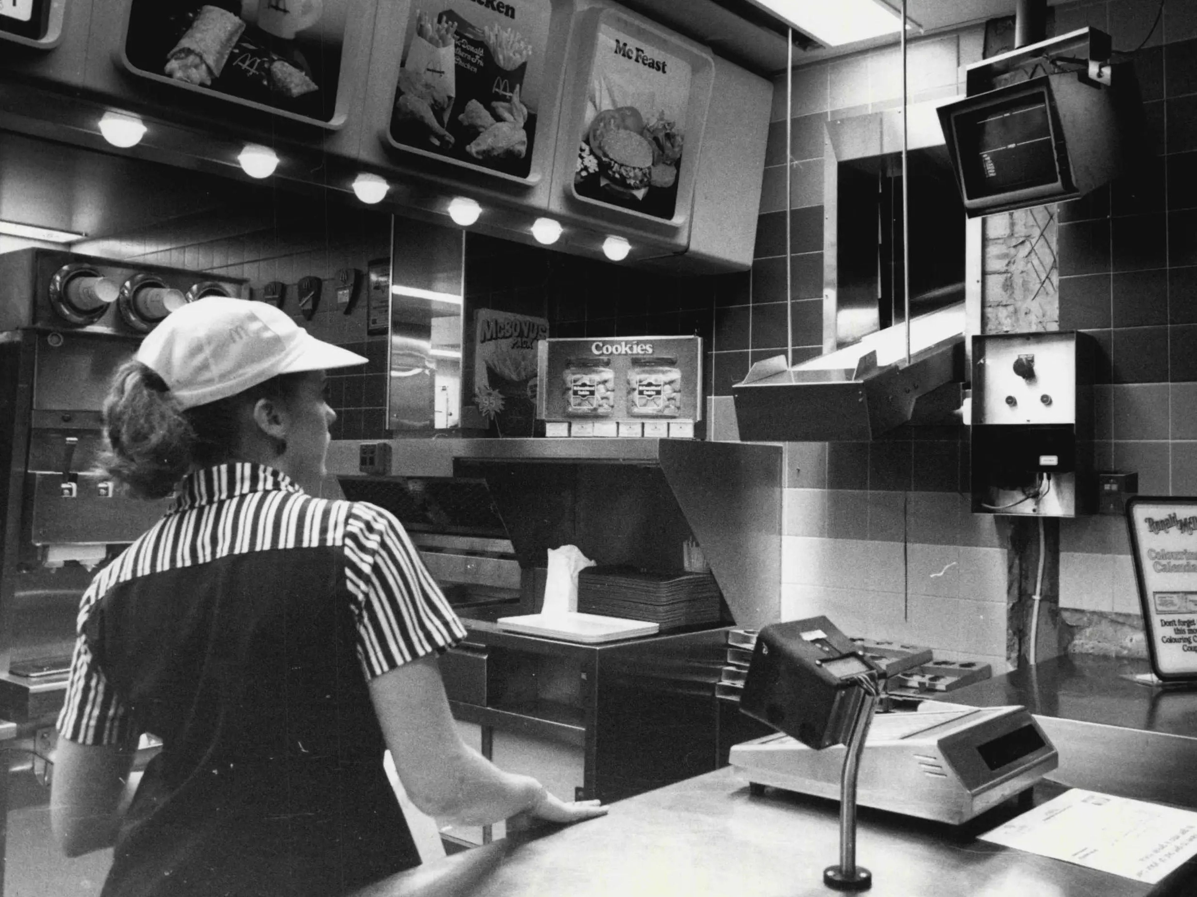 Un empleado coloca los pedidos en una cinta transportadora que entrega la comida en la sección McAuto del McDonald's en 1984.