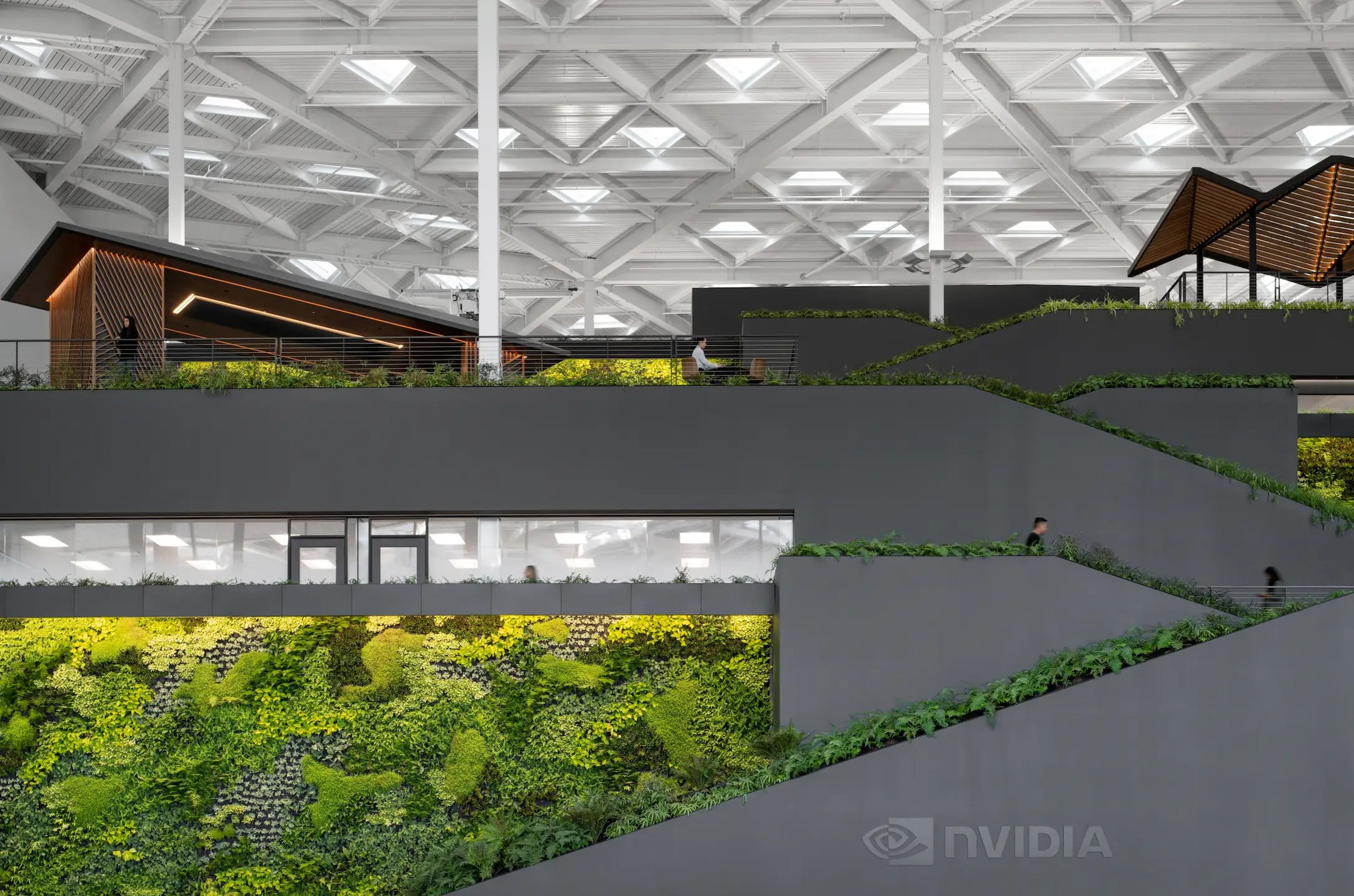 gray walkways inside Nvidia's headquarters, which are surrounded by a lot of greenery and triangle-shaped windows on the roof