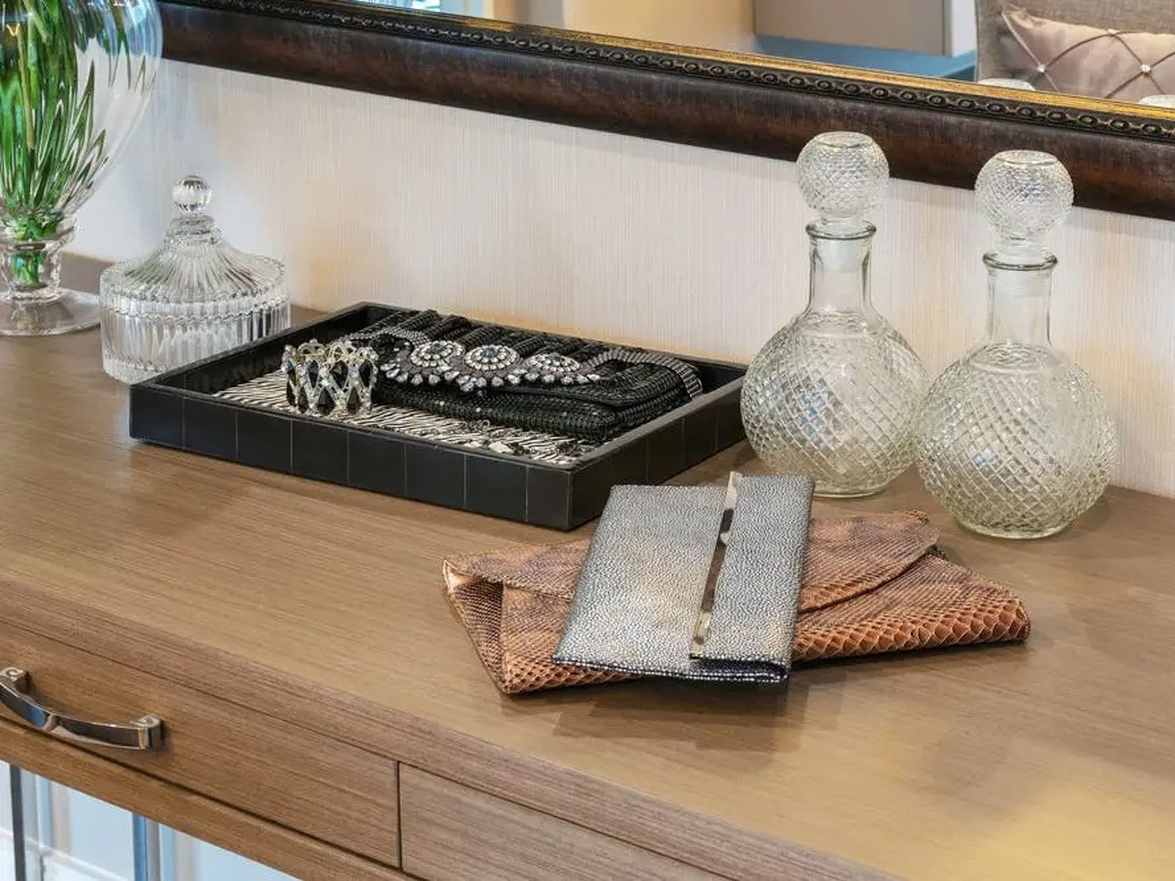 Joyas y bolsos de mano sobre una cómoda de madera.