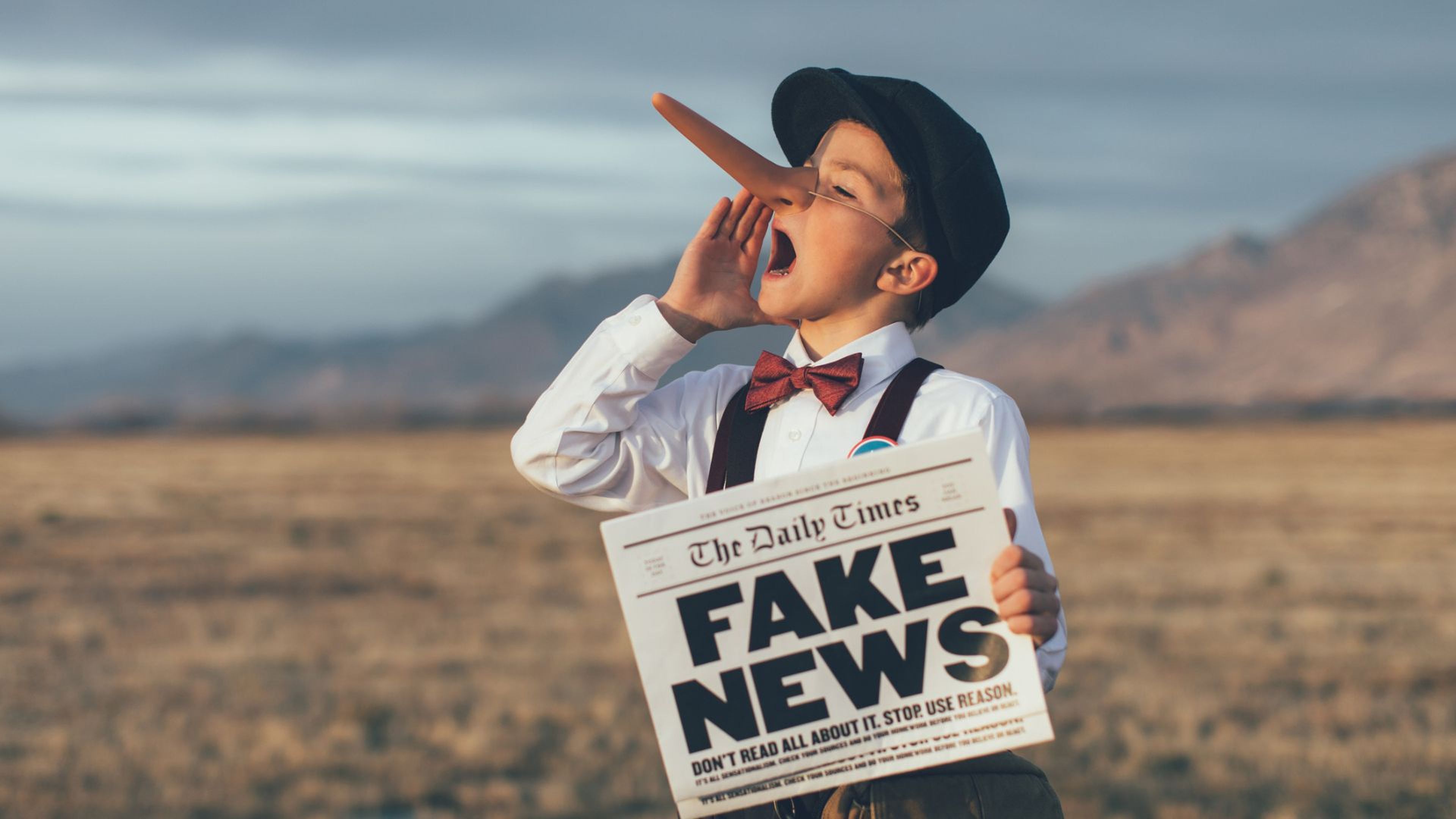 Un niño con la nariz de Pinocho y un periódico en el que pone 'fake news'.