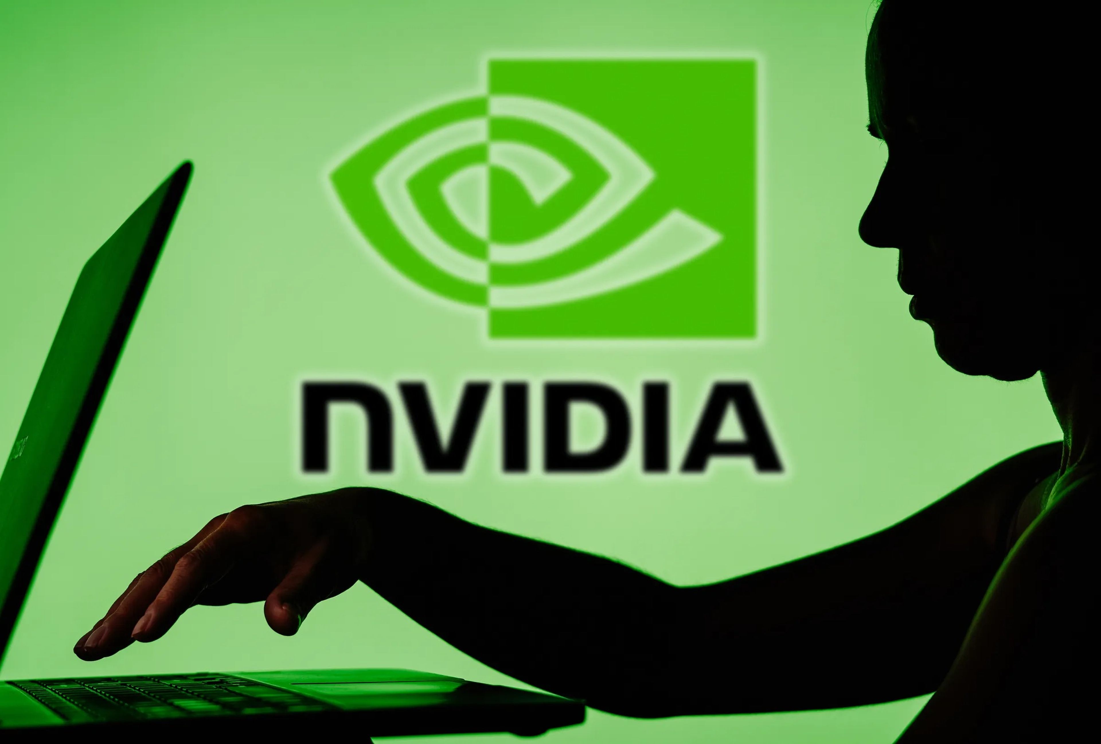 Silueta de una persona utilizando un ordenador portátil frente al logotipo de Nvidia.