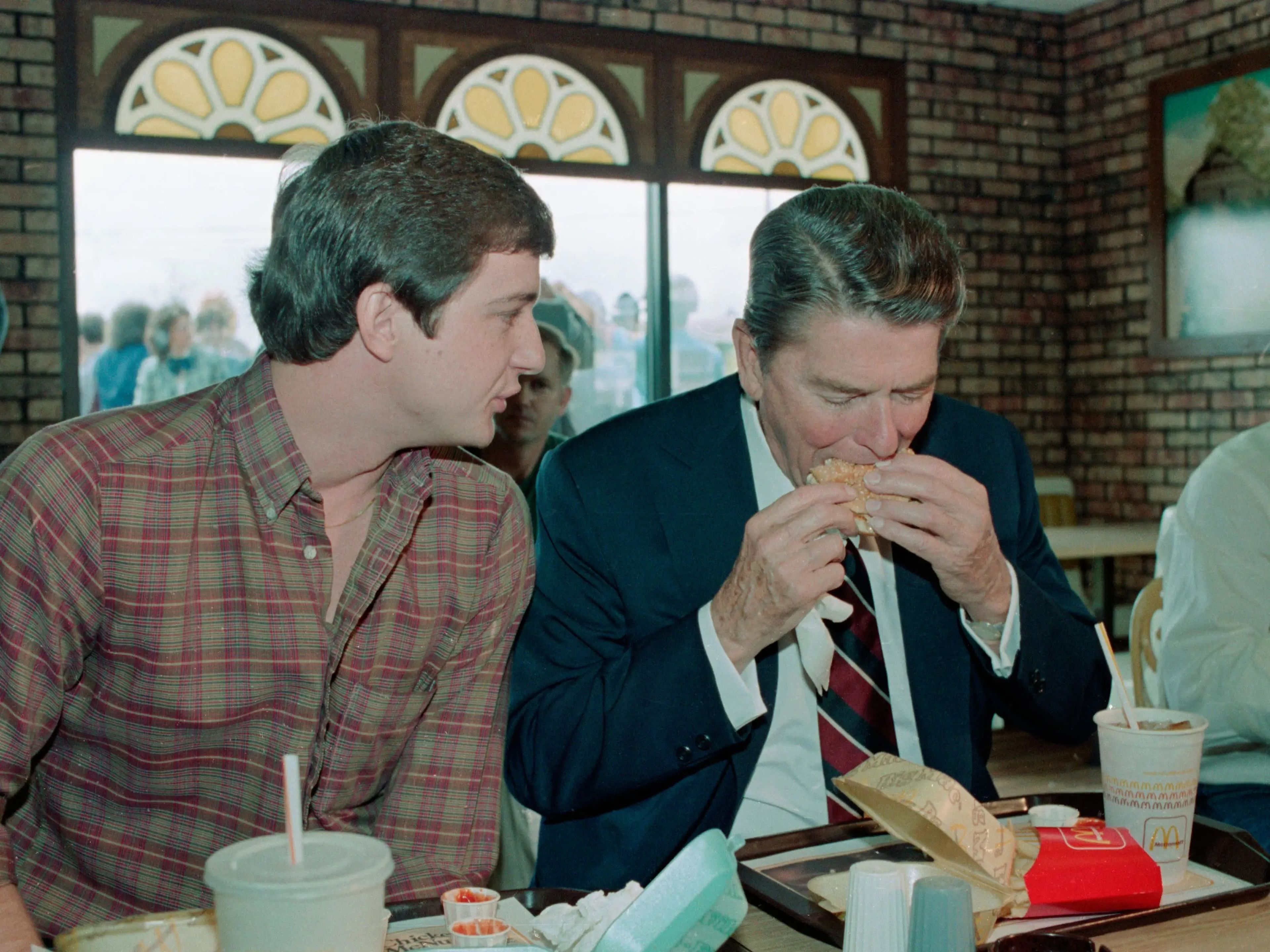 El presidente Ronald Reagan da un mordisco a un Big Mac, mientras Charles Patterson charla con él durante una breve parada de campaña en 1984.