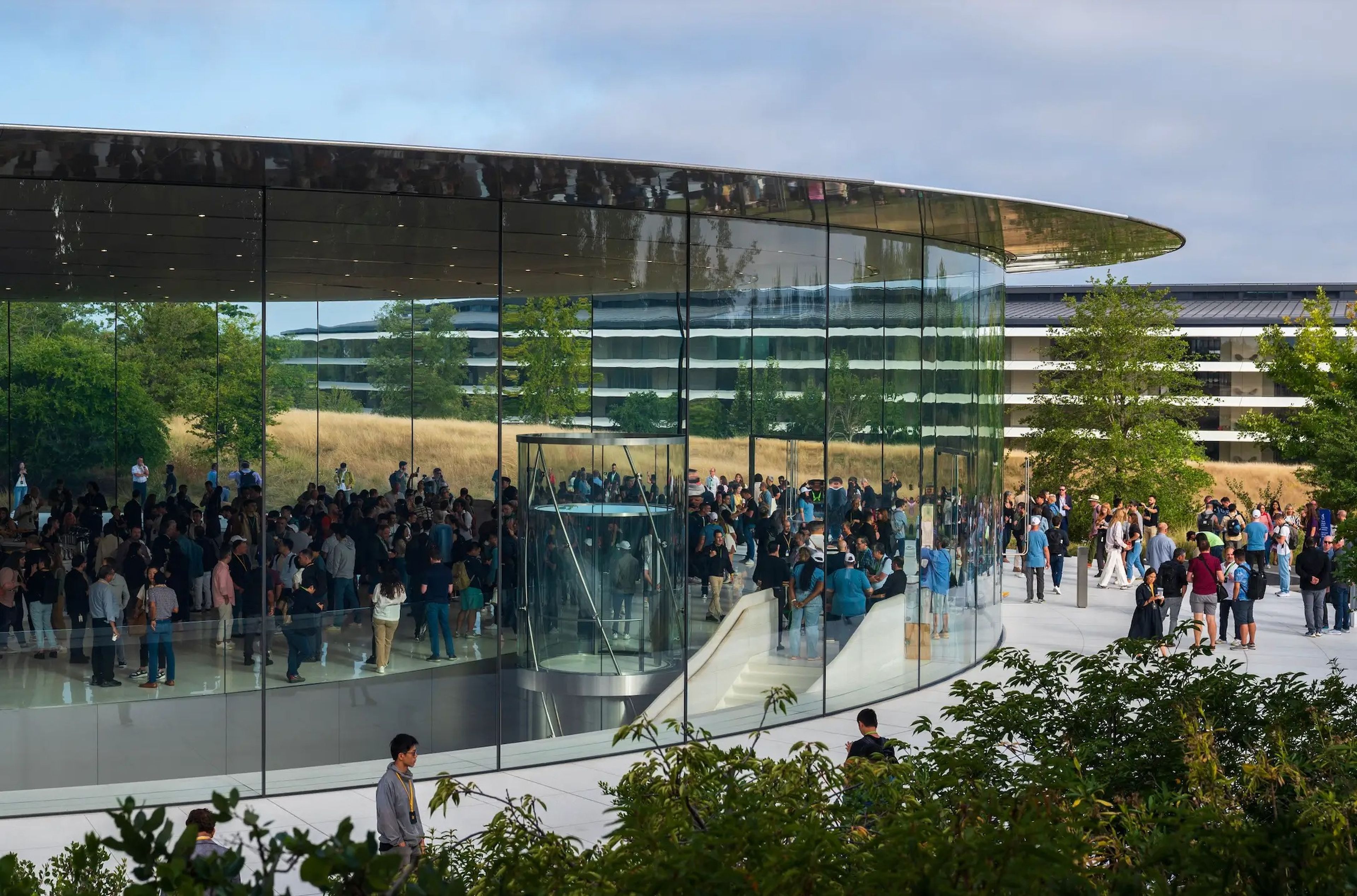 Un grupo de personas camina por el Steve Jobs Theater antes de un evento en el campus de Apple Park.