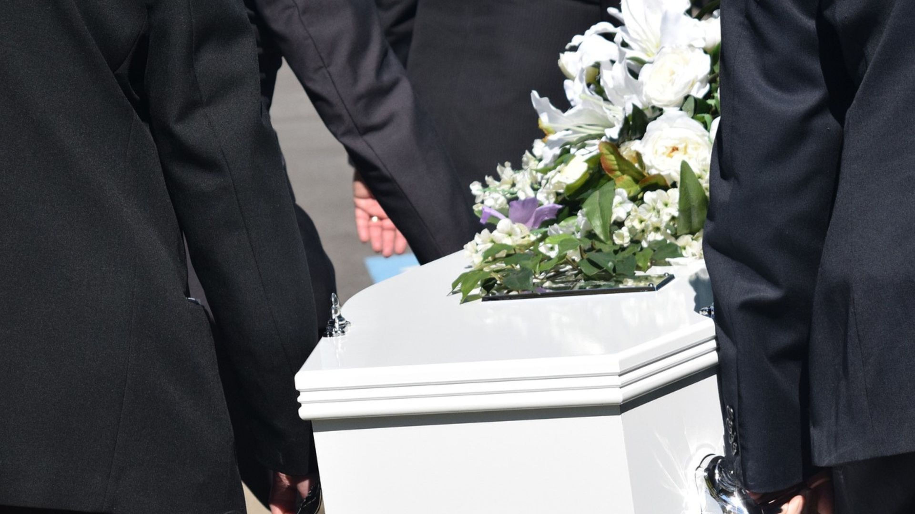 Varias personas llevan un ataud en un funeral.