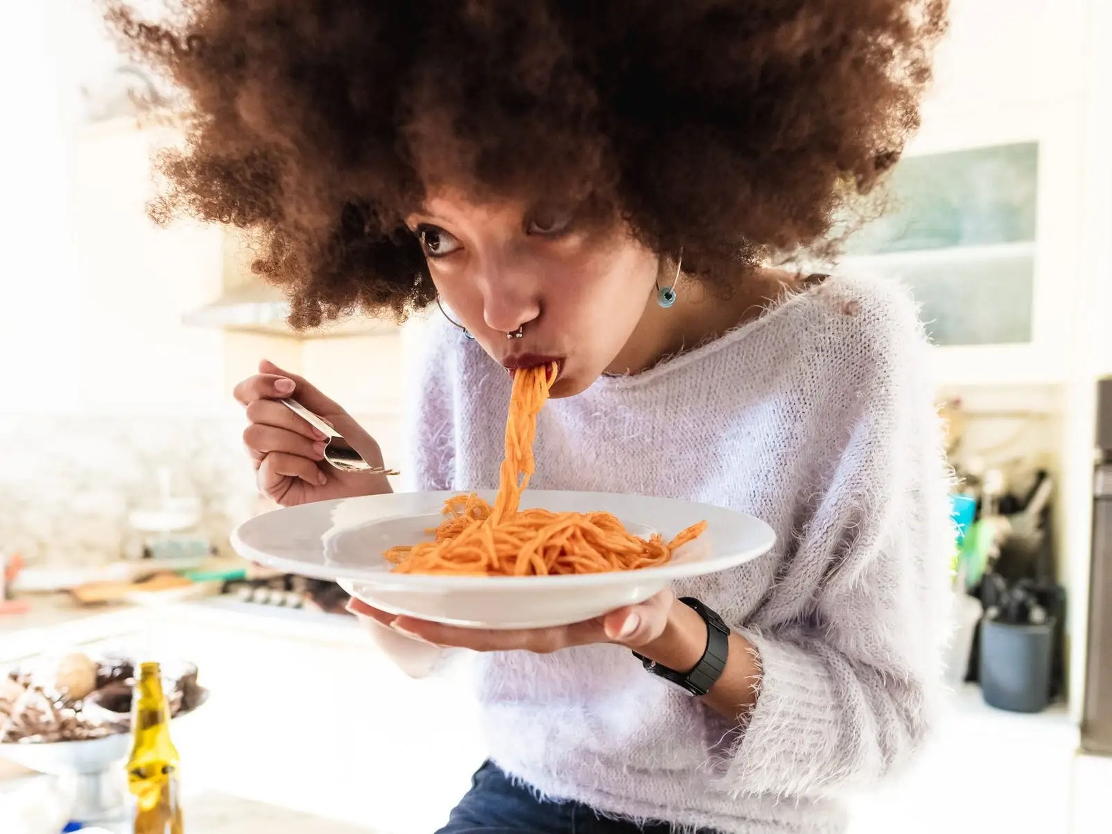 A woman eating a plate of tomato spaghetti.