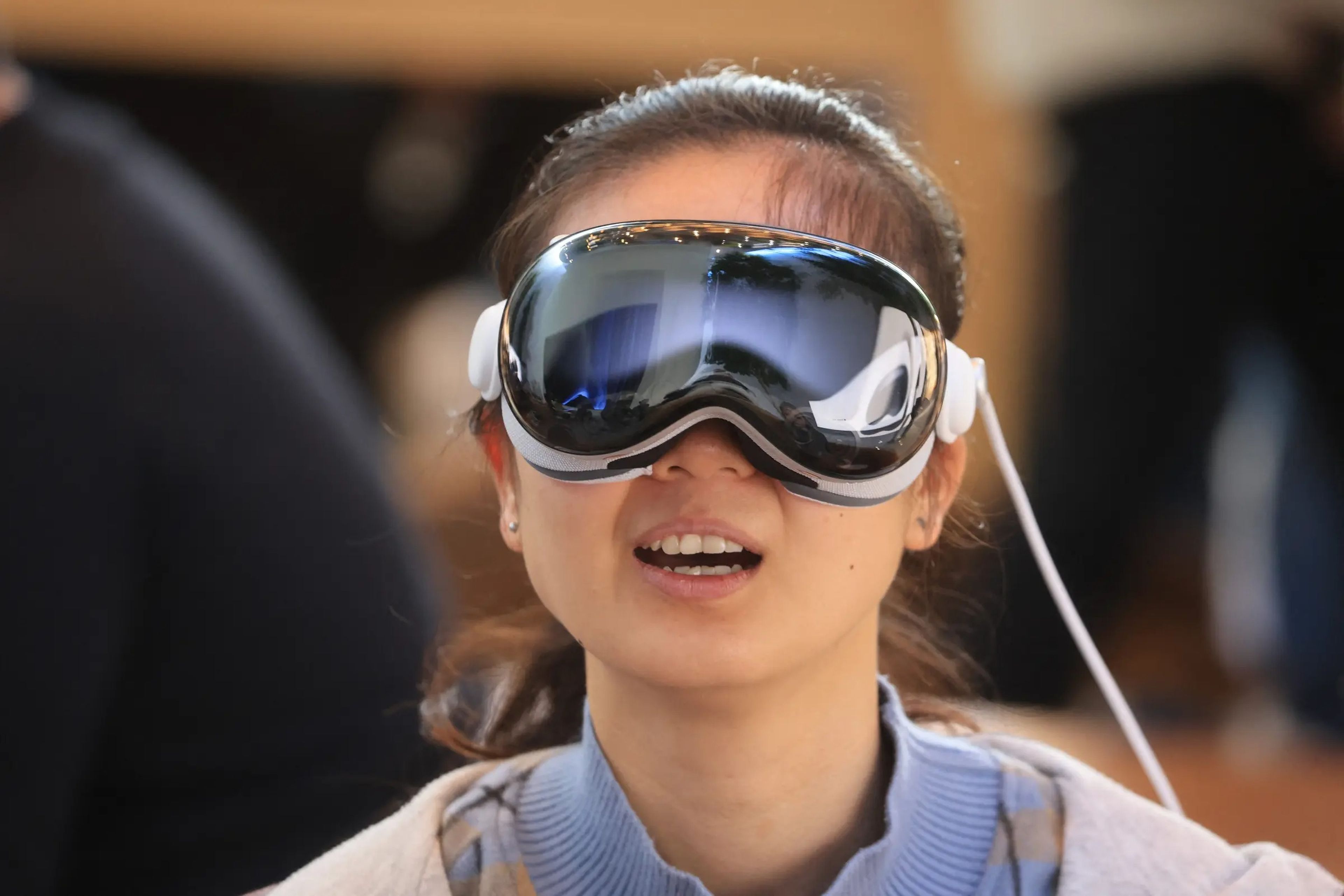 A young woman tries on an Apple Vision Pro headset.