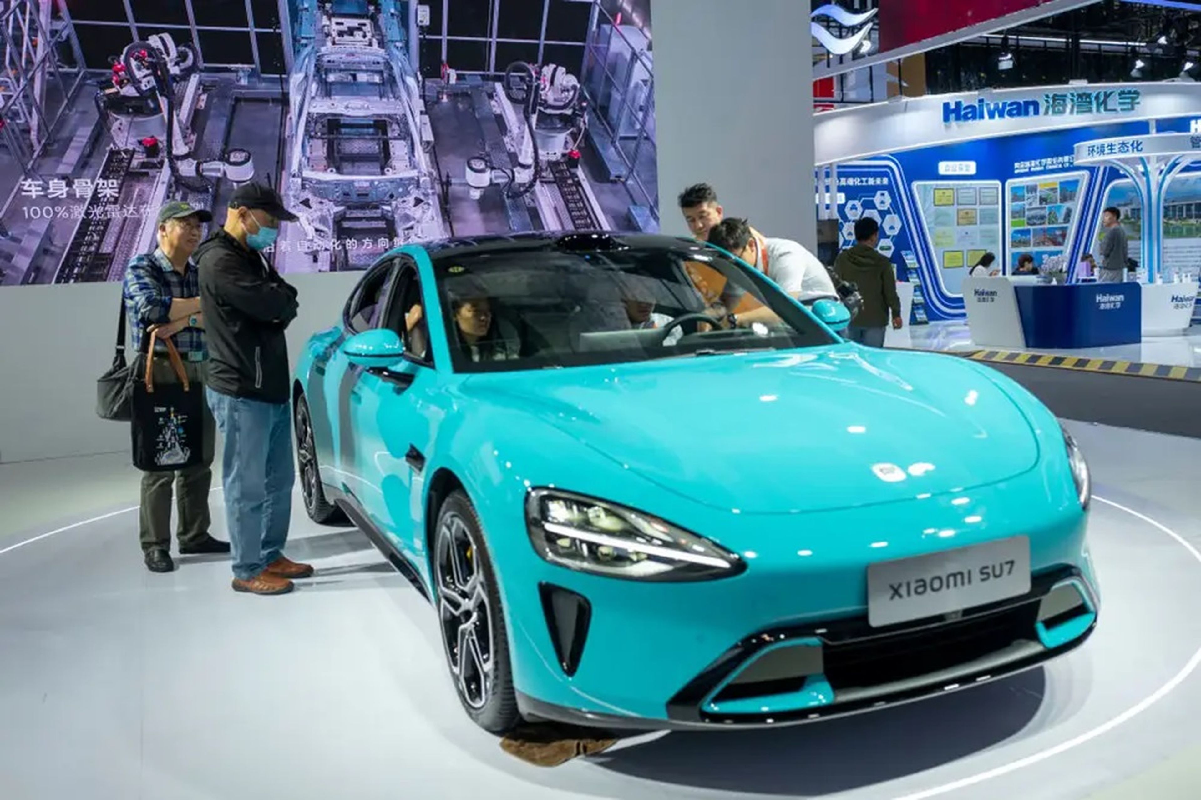 Asistentes al salón del automóvil de Pekín examinan el SU7, el primer coche eléctrico fabricado por la empresa china de teléfonos inteligentes Xiaomi.