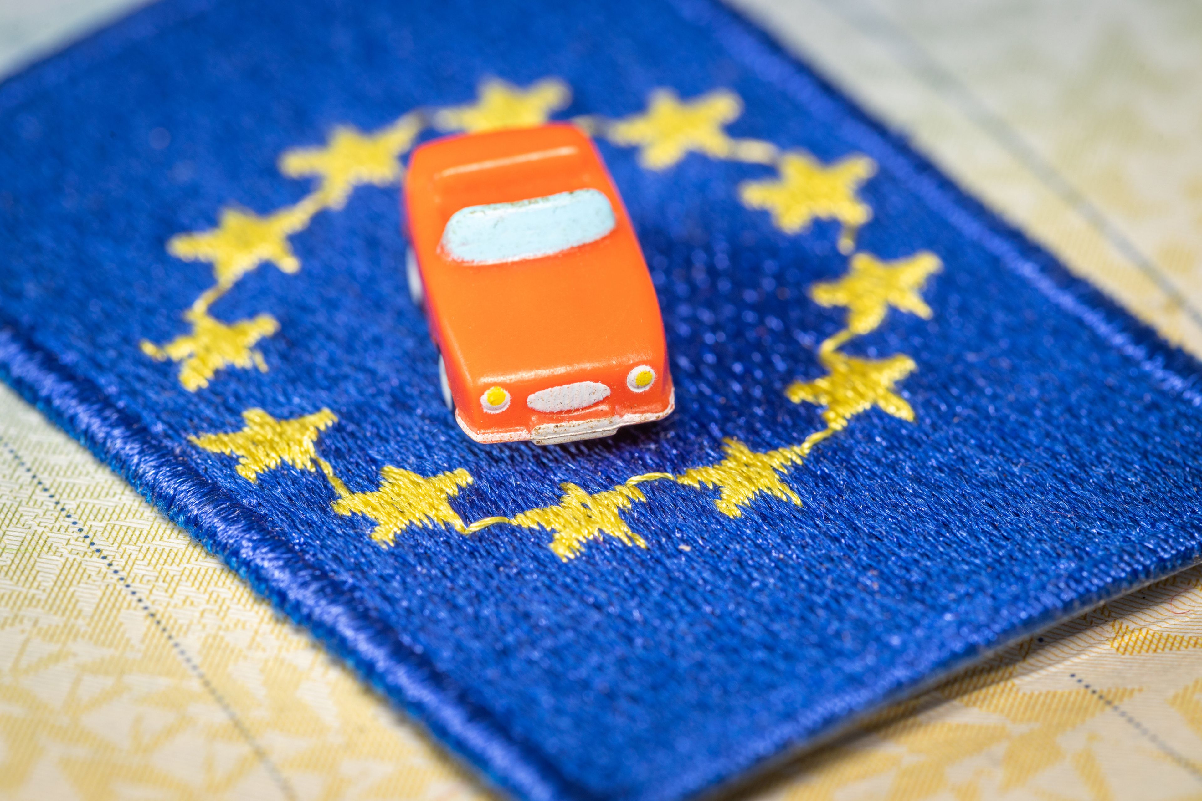 Un coche encima de una bandera de la Unión Europea.