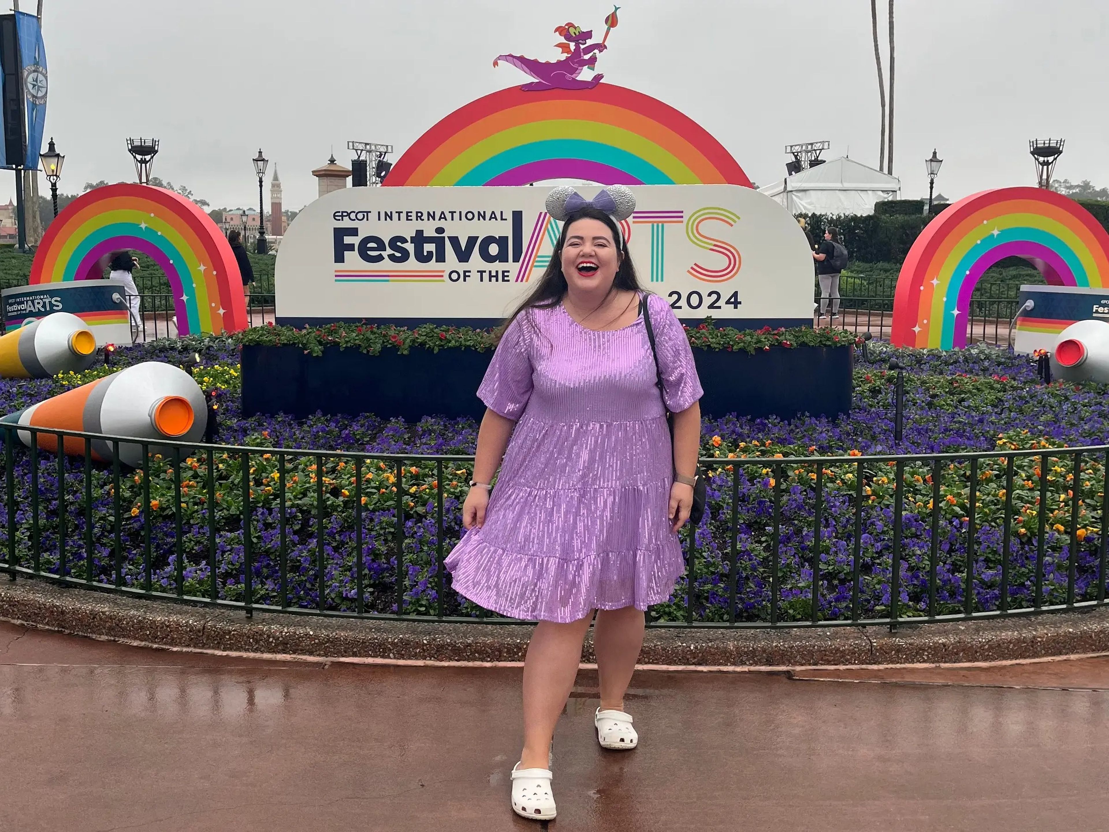 megan dubois posing in front of the rainbow festival of th arts sign at epcot in disney world