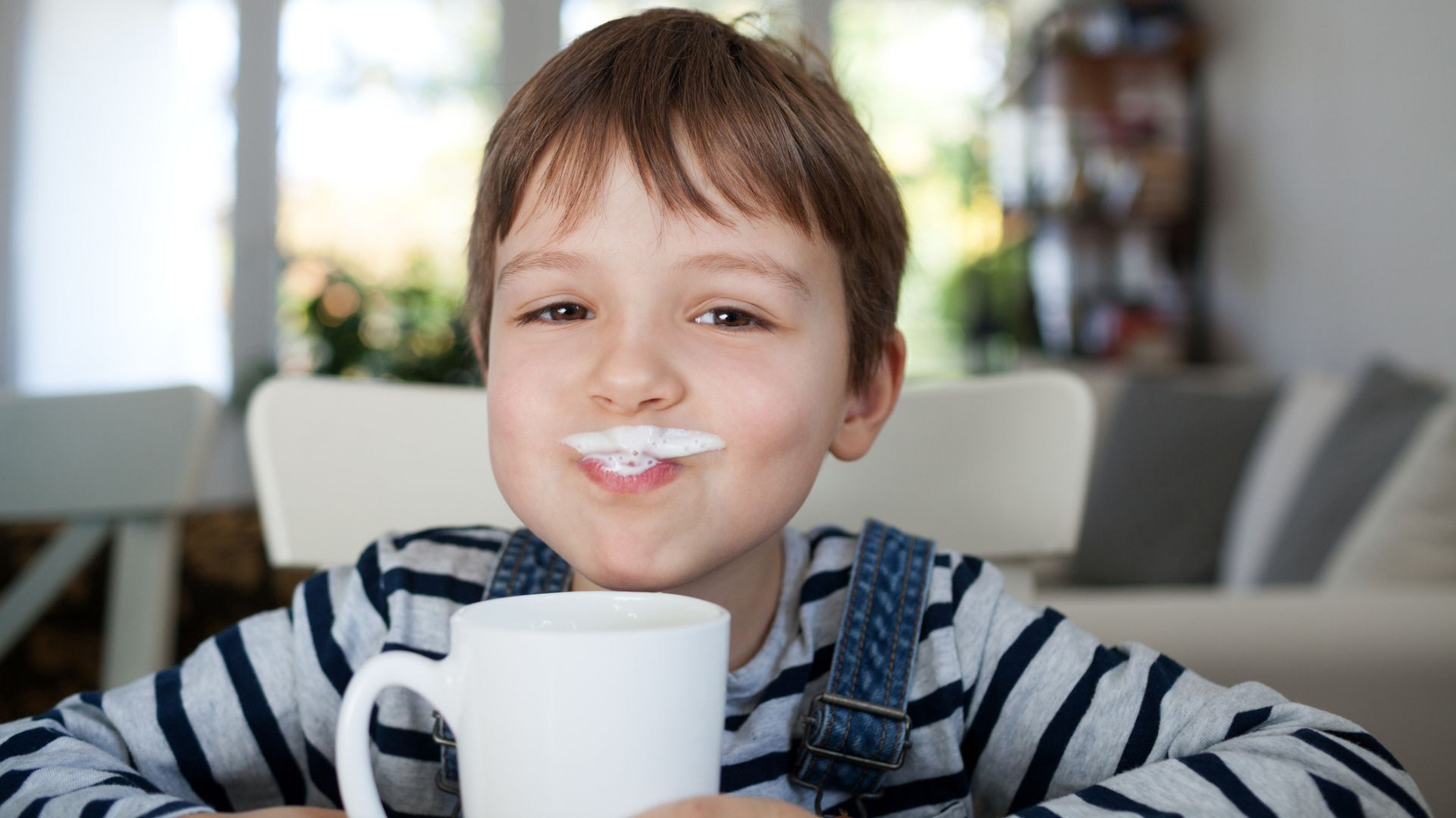 Un niño bebe un tazón de leche.