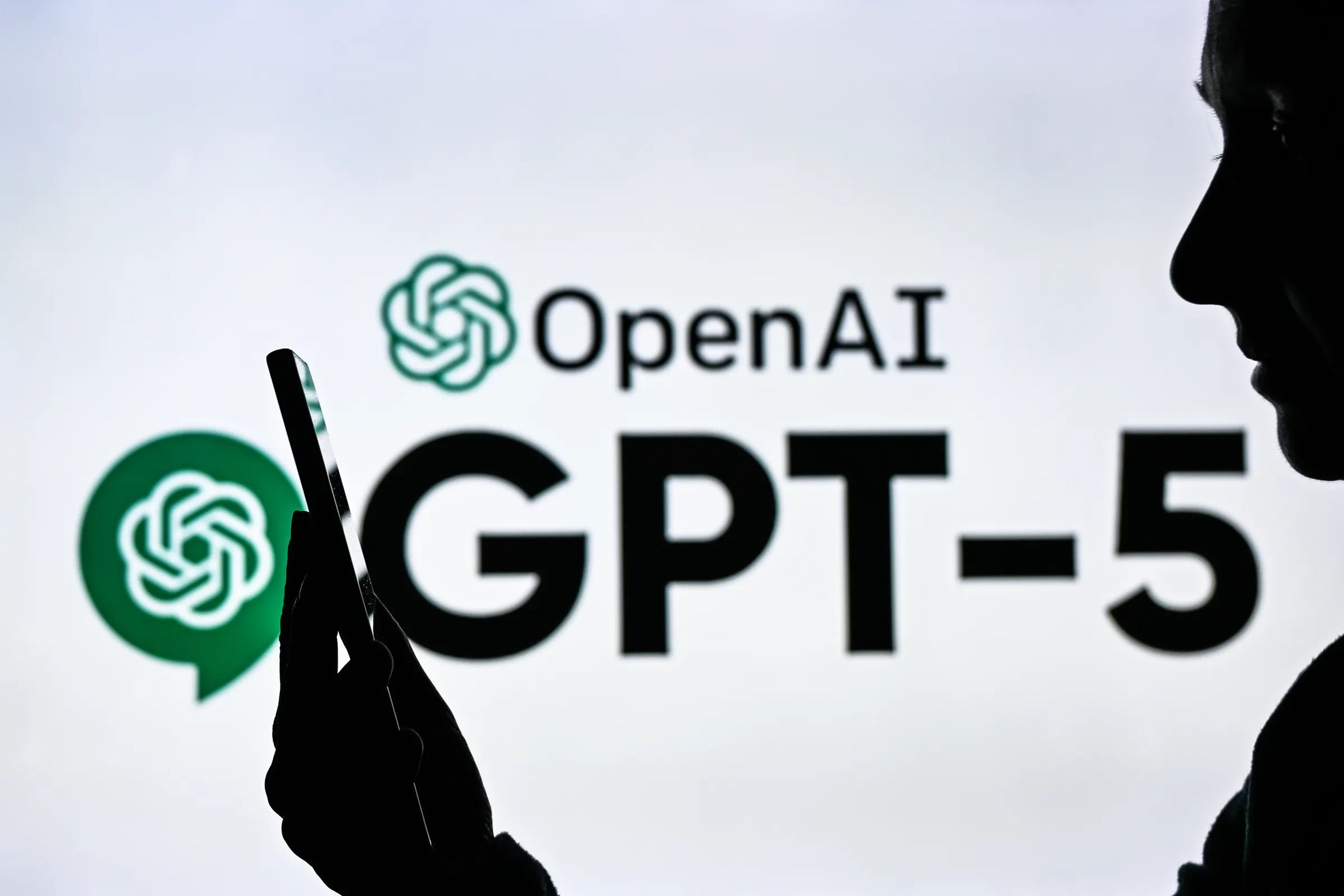OpenAI logo with text that says GPT-5 behind a person holding a phone