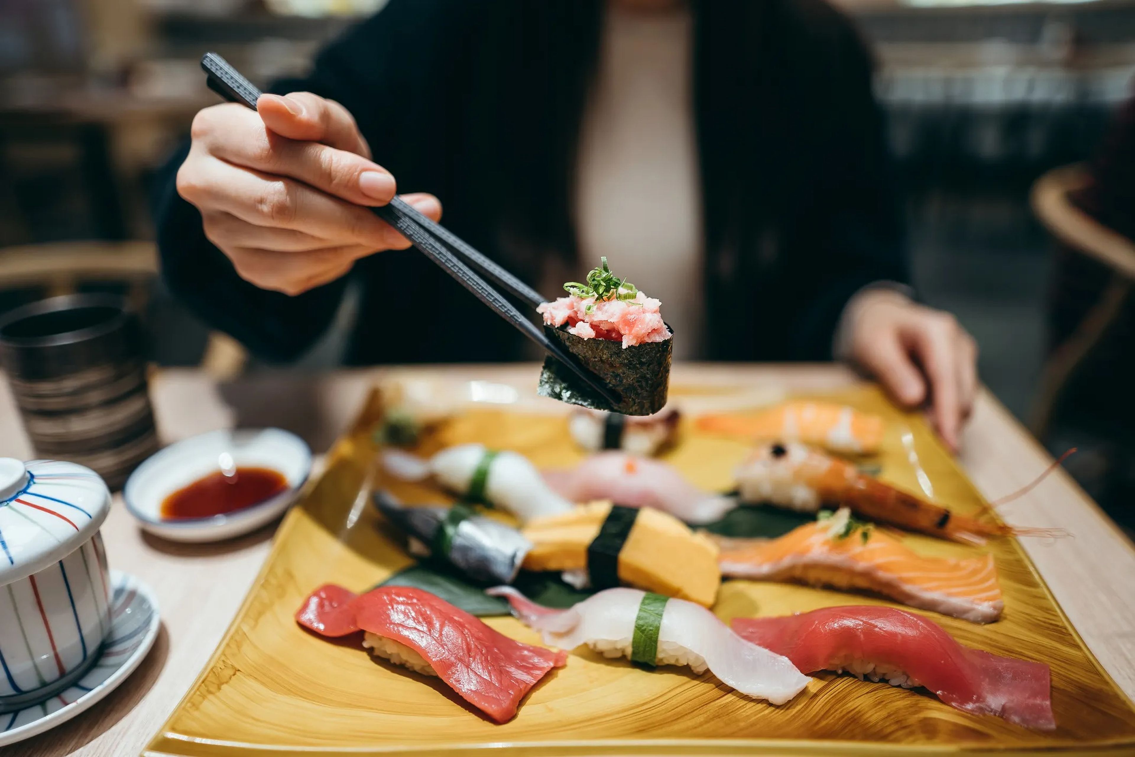 Person holding sushi in chopsticks