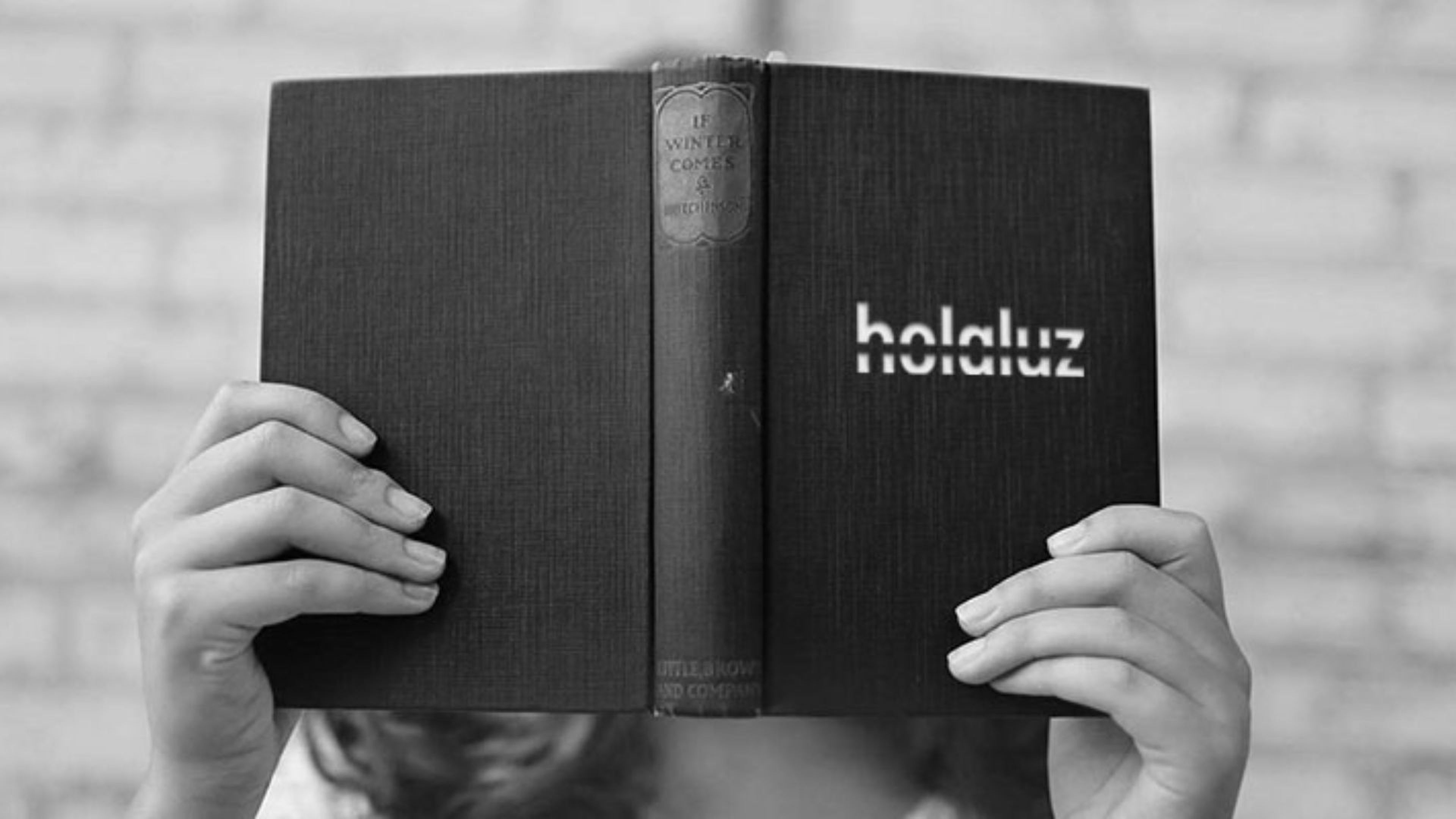 Una persona se tapa la cara con un libro titulado Holaluz.