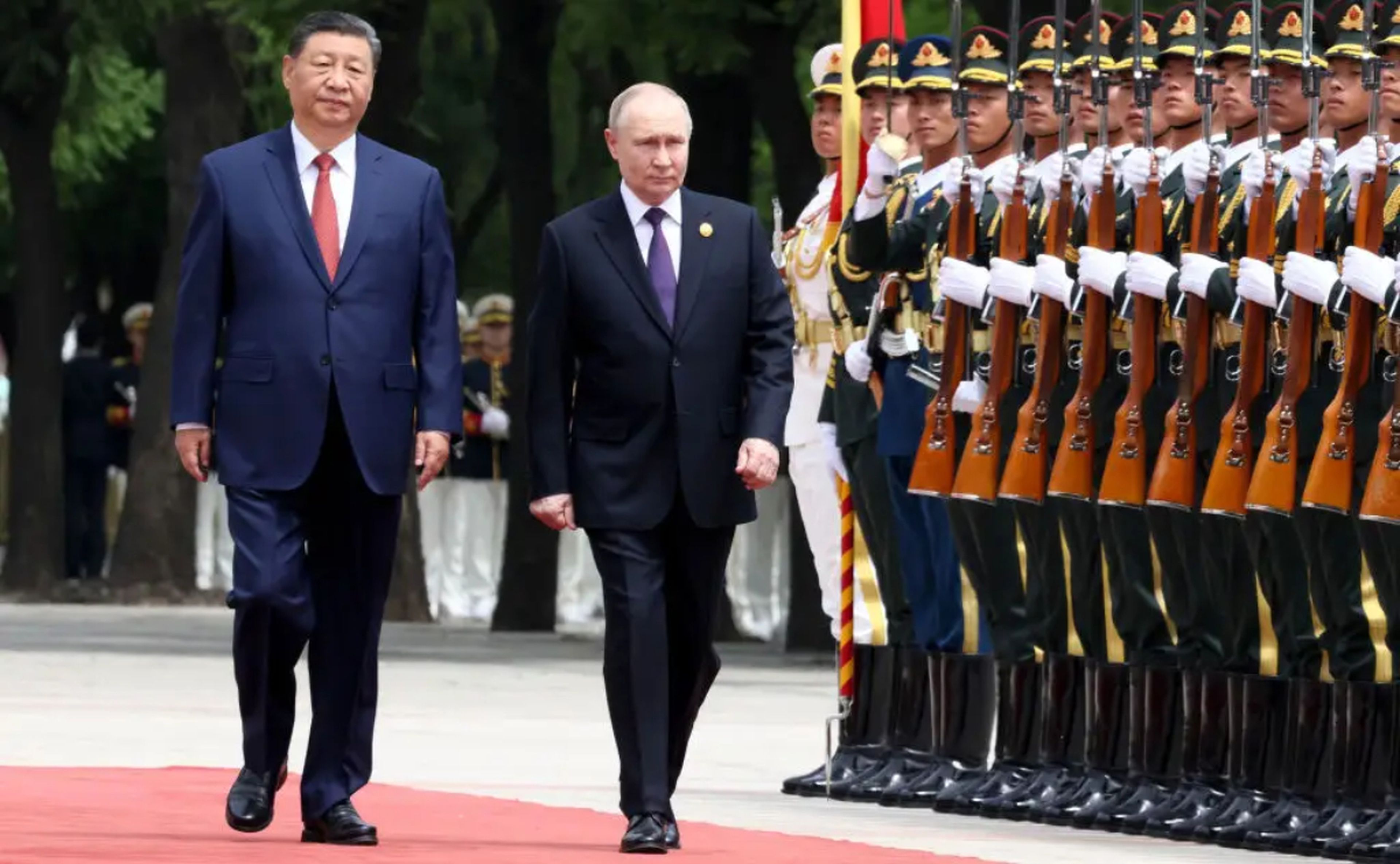 El presidente ruso Vladímir Putin (dcha.) es recibido con alfombra roja por un séquito ceremonial en Pekín, China, el 16 de mayo de 2024. 