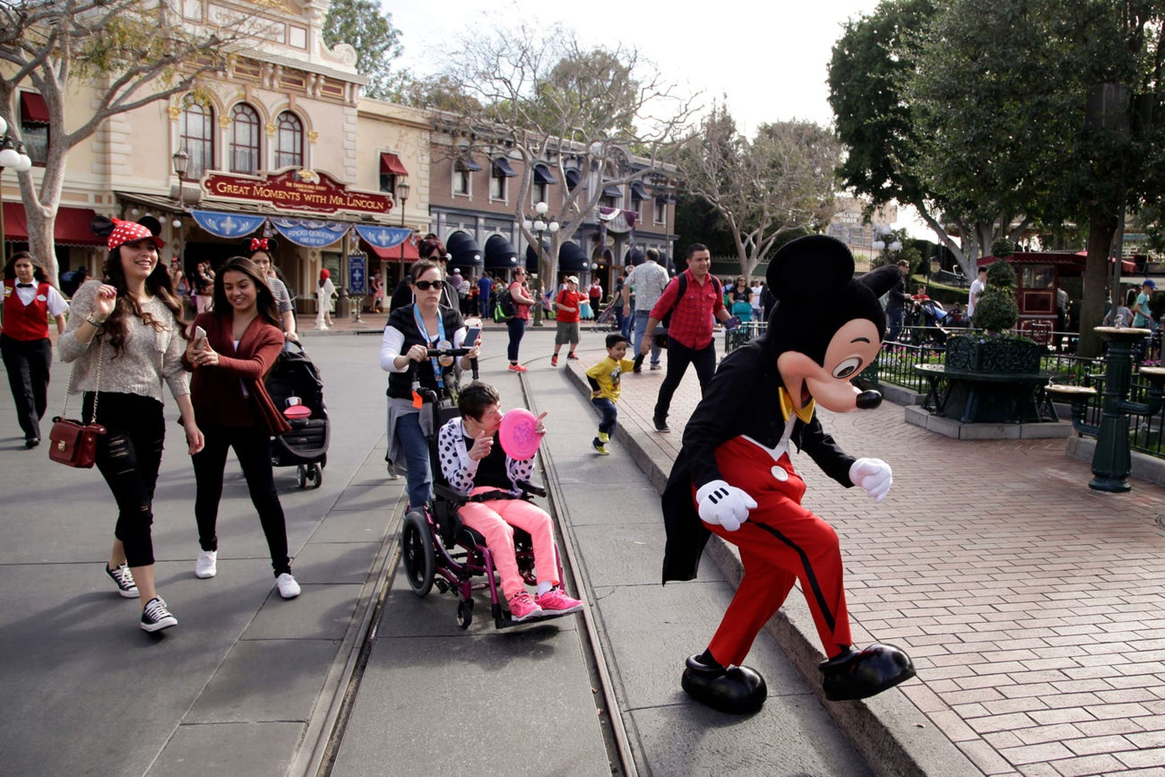 Visitantes siguen a Mickey Mouse para hacerse fotos en Disneyland en Anaheim, California. 