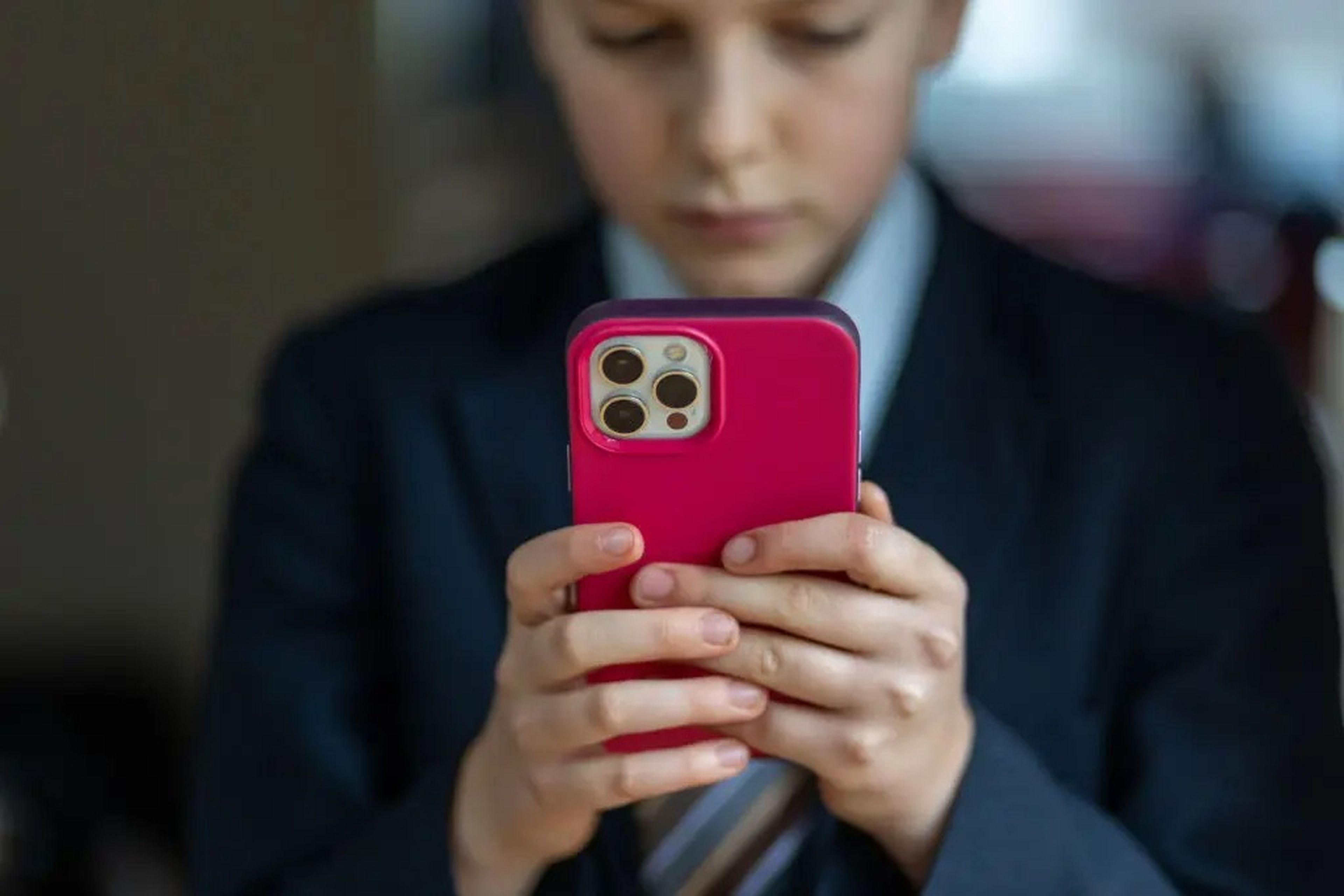 Un chico joven sujetando un teléfono rojo.