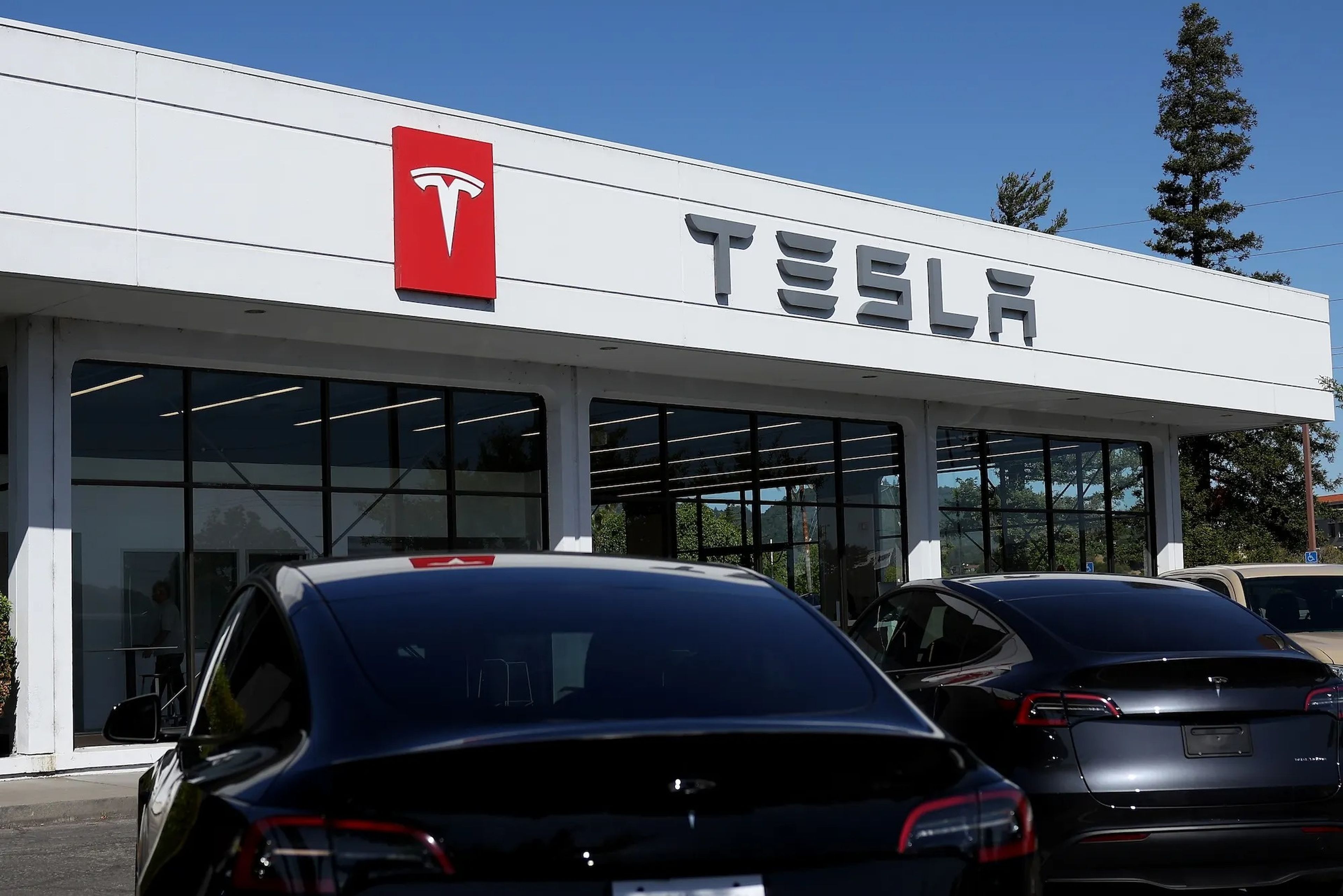 Brand new Tesla vehicles are parked outside a Tesla dealership.