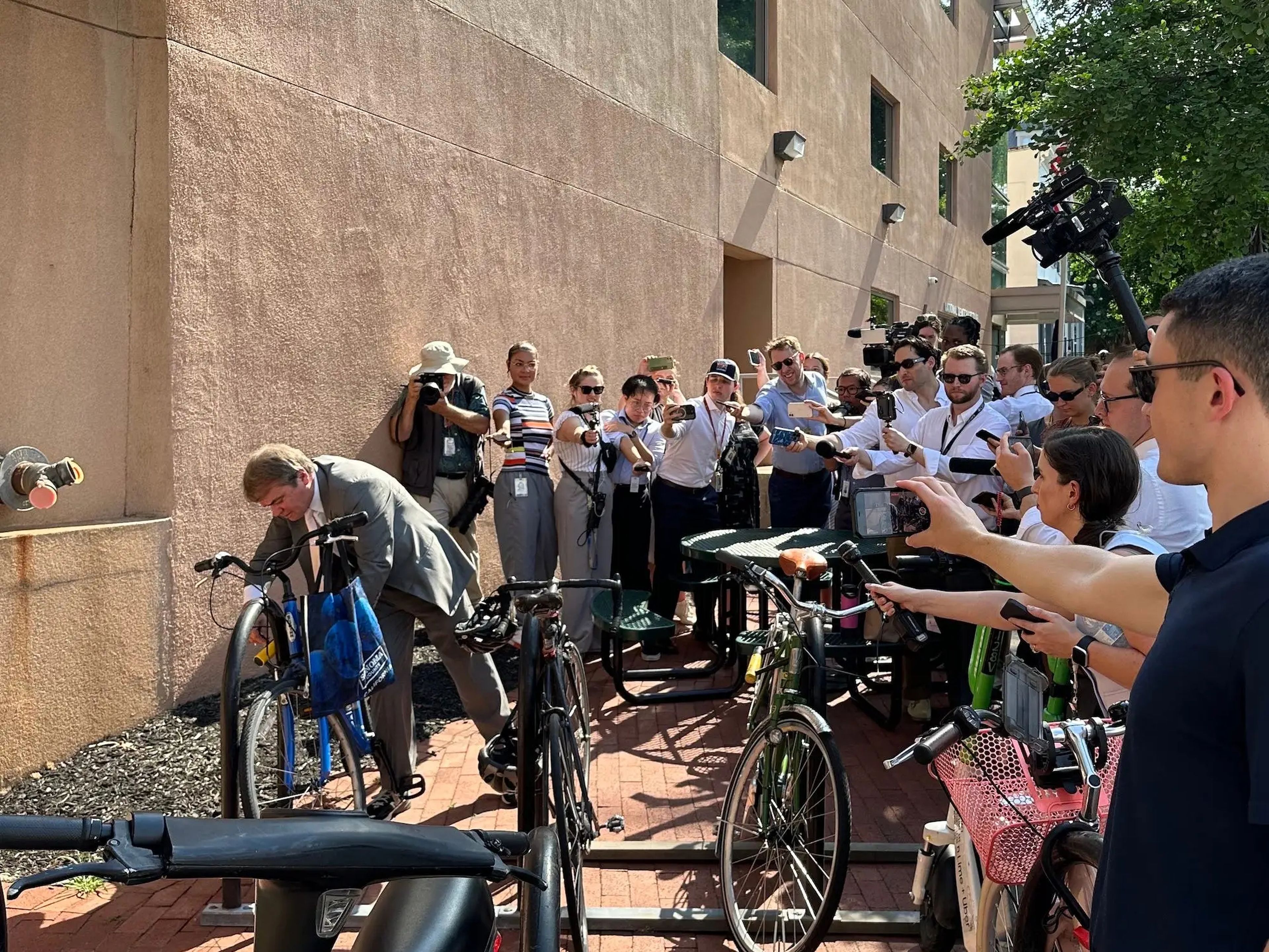 El congresista Mike Quigley responde a las preguntas de los periodistas mientras desbloquea su bicicleta frente a la sede del Comité Nacional Demócrata. 