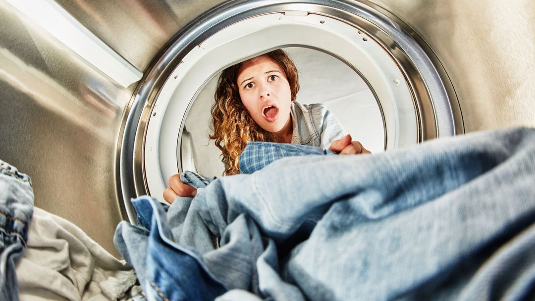 Una mujer mete la ropa en una secadora.