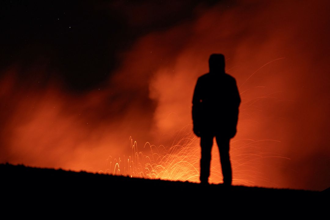 Una persona observa cómo sale humo y lava del cráter del Etna, el volcán más activo de Europa, en Italia.