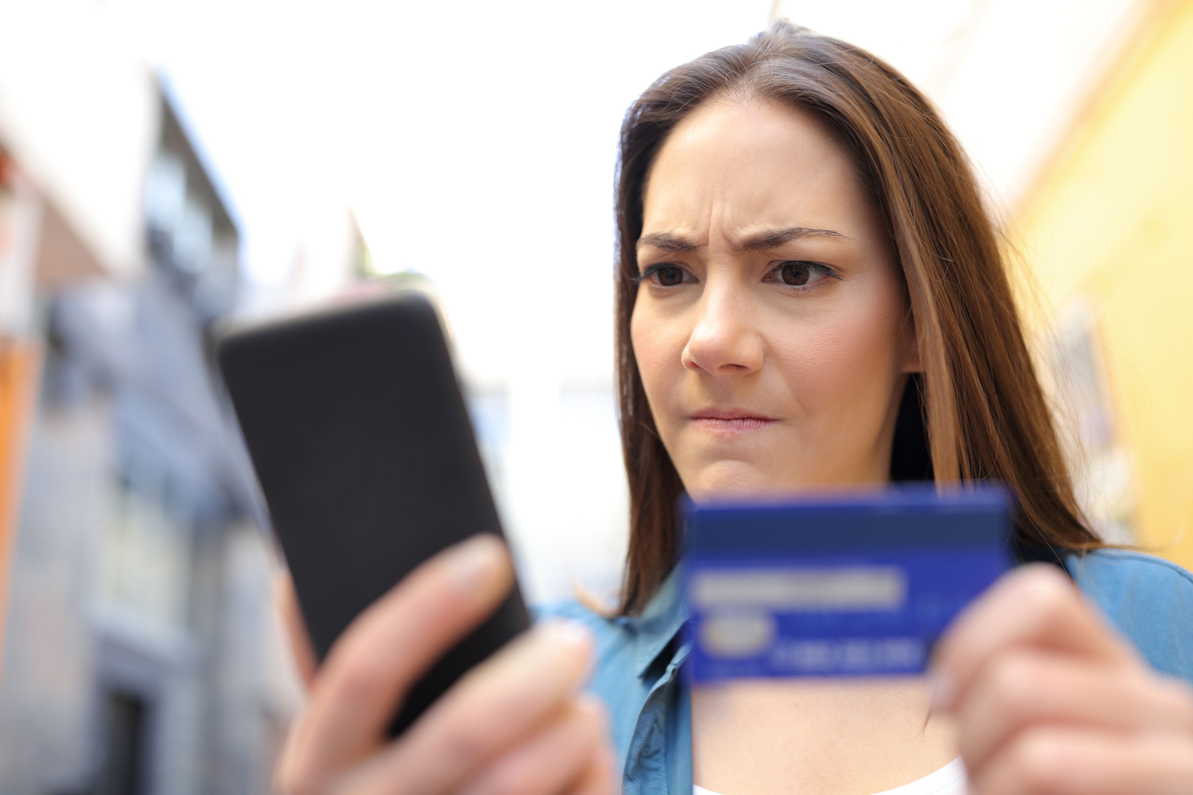 Mujer enfadada con la tarjeta y su banco en el móvil.