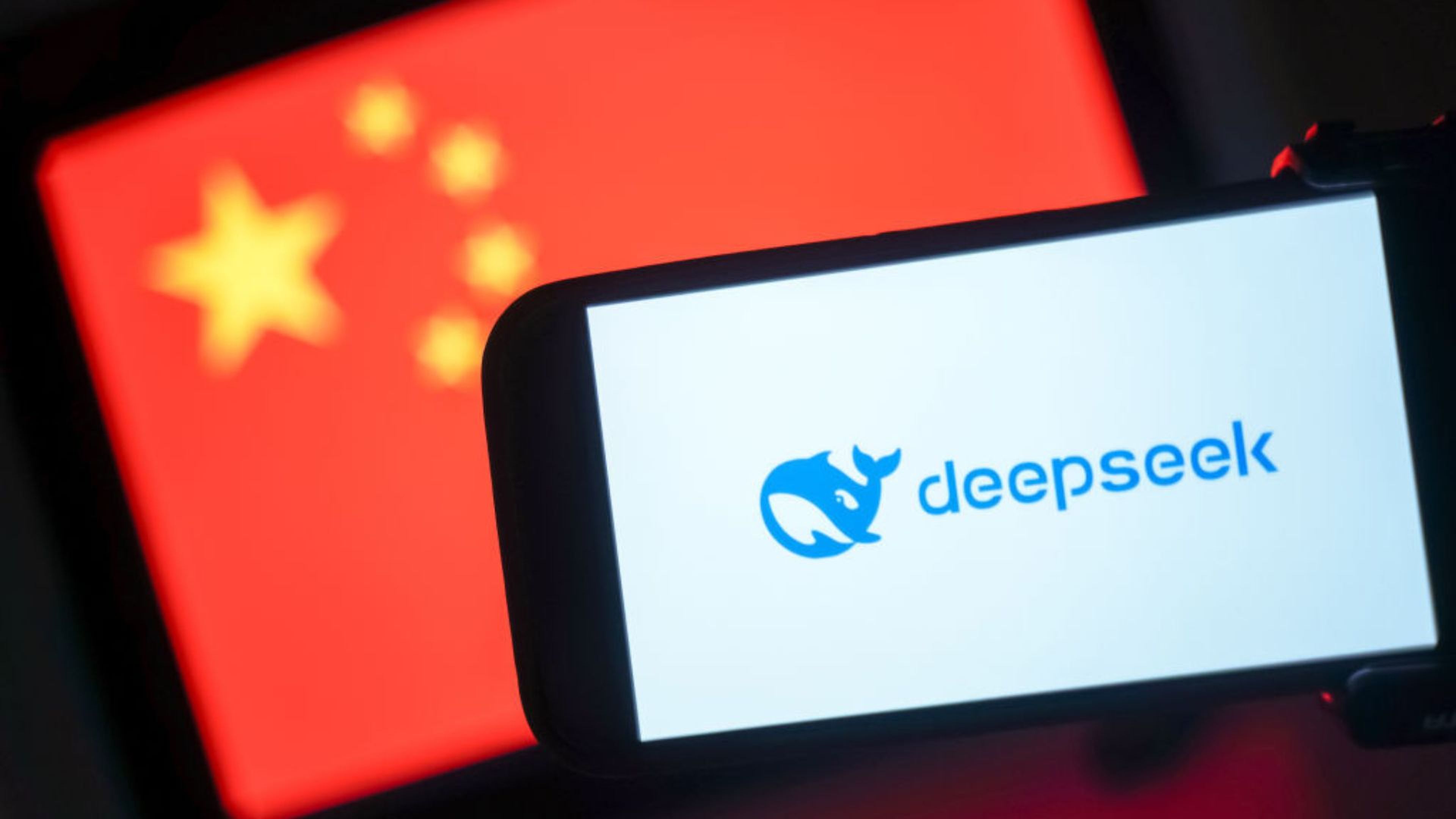 Un móvil con Deepseek en la pantalla y una bandera china detrás. 