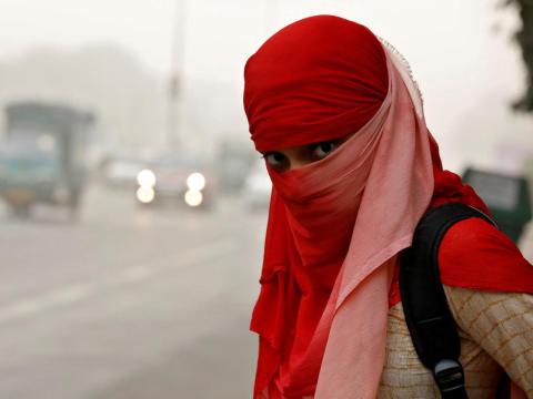A woman waits for a bus on a smoggy morning in New Delhi.
