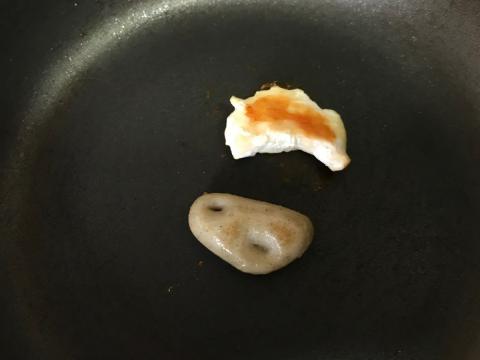 Un prototipo de pieza de pechuga de pollo vegetal (abajo), al lado de una pieza de pechuga de pollo tradicional (arriba), cocinándose en una sartén.