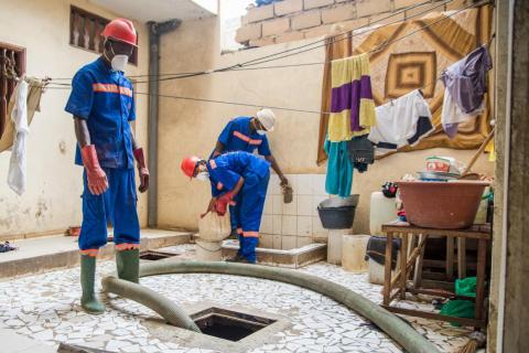 El recolector de desechos Assane Cissé (izquierda) y Mariama Seck aspiran los desechos humanos de un depósito dentro de un patio. Esa basura será transportada al procesador Omni en Dakar.