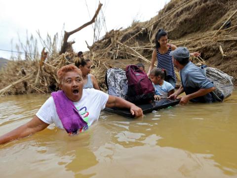 Marta Sostre Vazquez reacts as she wades into the San Lorenzo Morovis river with her family, after the bridge was swept away by Hurricane Maria in Morovis, Puerto Rico, Wednesday, Sept. 27, 2017.