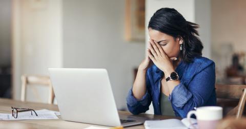Mujer con las manos en la cabeza frente al ordenador Mujer con las manos en la cabeza frente al ordenador